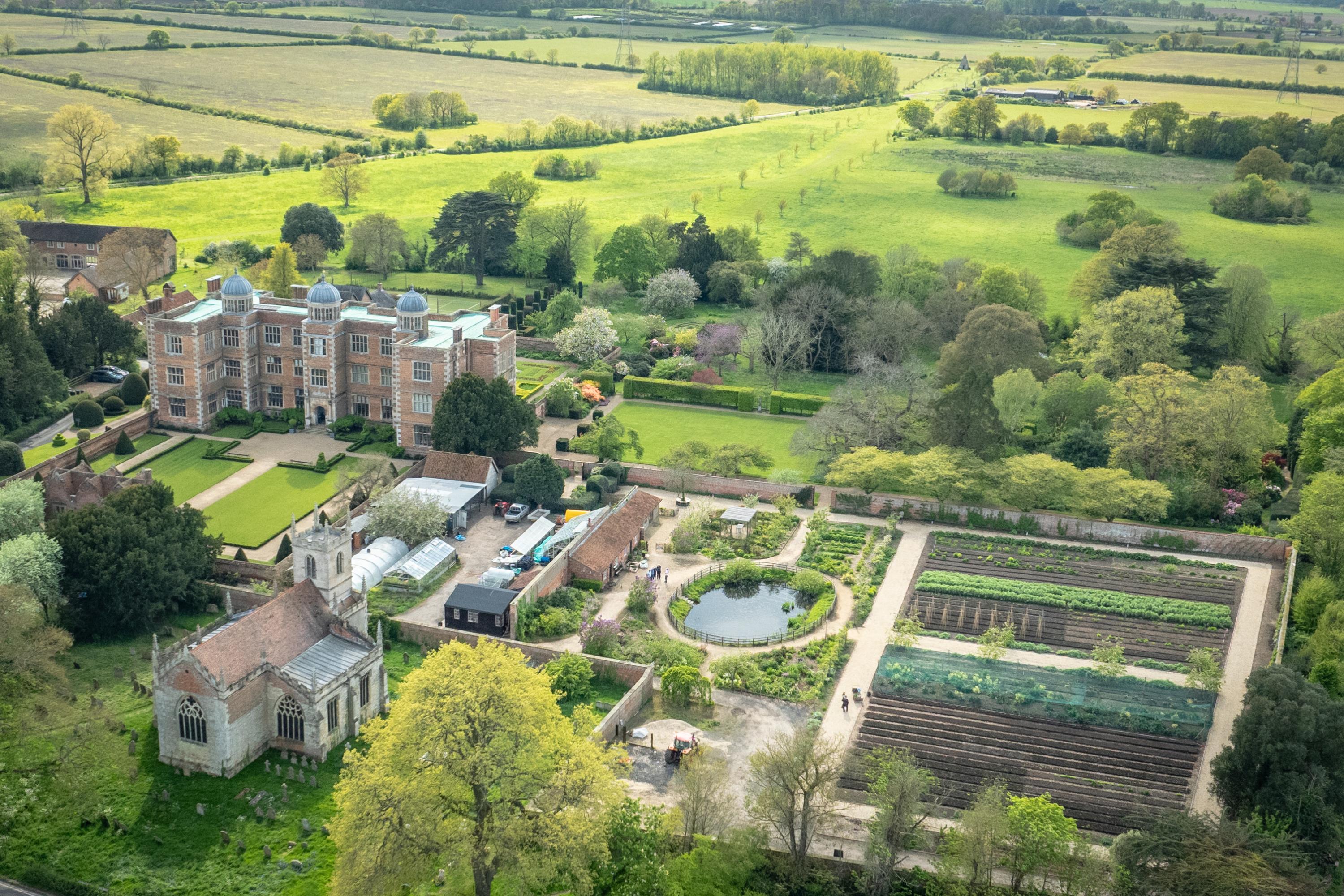 A drone photograph of Doddington Hall featuring the Hall, the Church, and a walled kitchen garden.