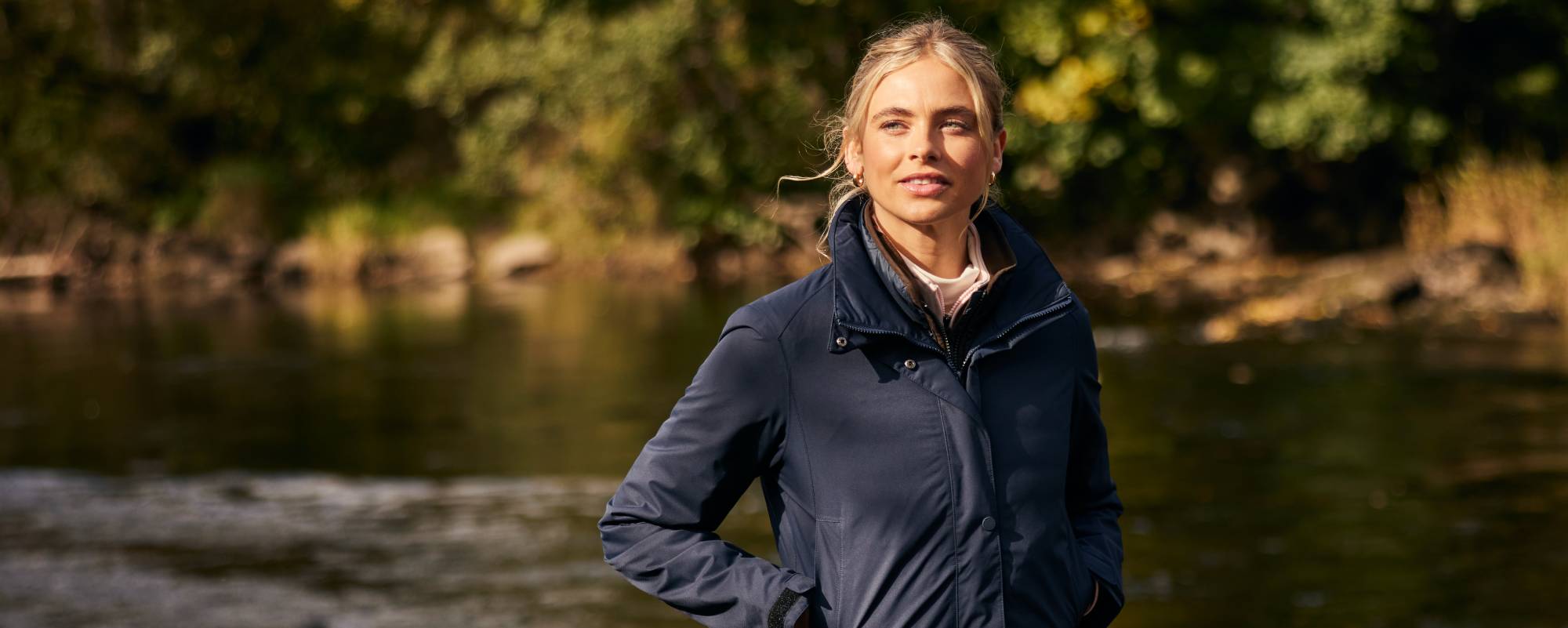 An image of a lady wearing a navy jacket on a rivers edge.