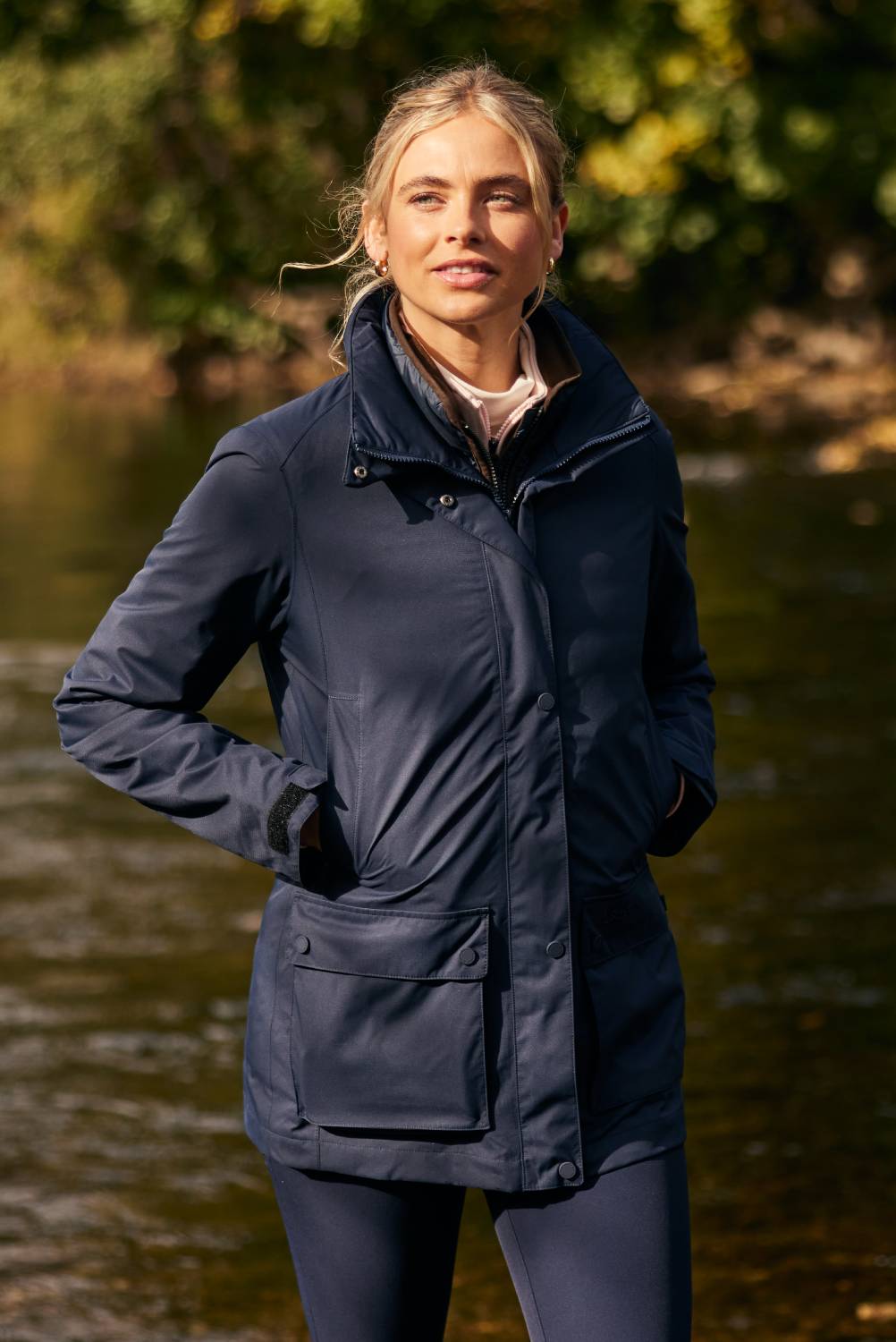 An image of a lady wearing a navy jacket on a rivers edge.