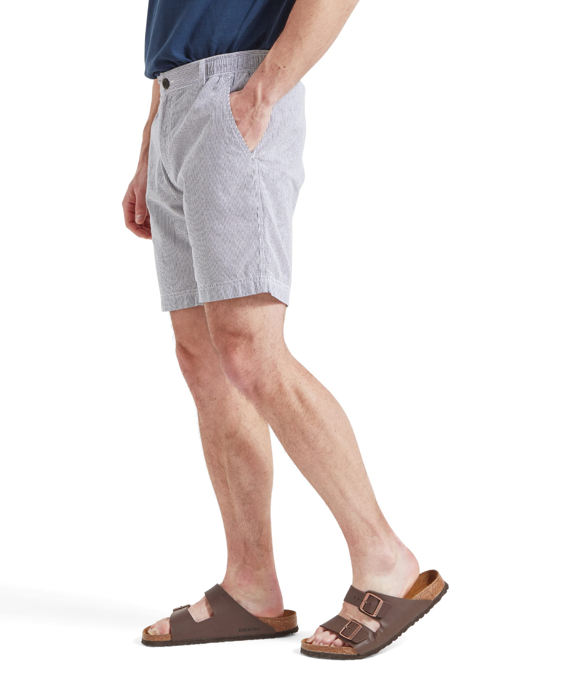 A side view of a man wearing the Schöffel Abersoch Shorts for Men in Navy, with his hands in his pockets. He is also wearing a blue shirt and brown sandals.