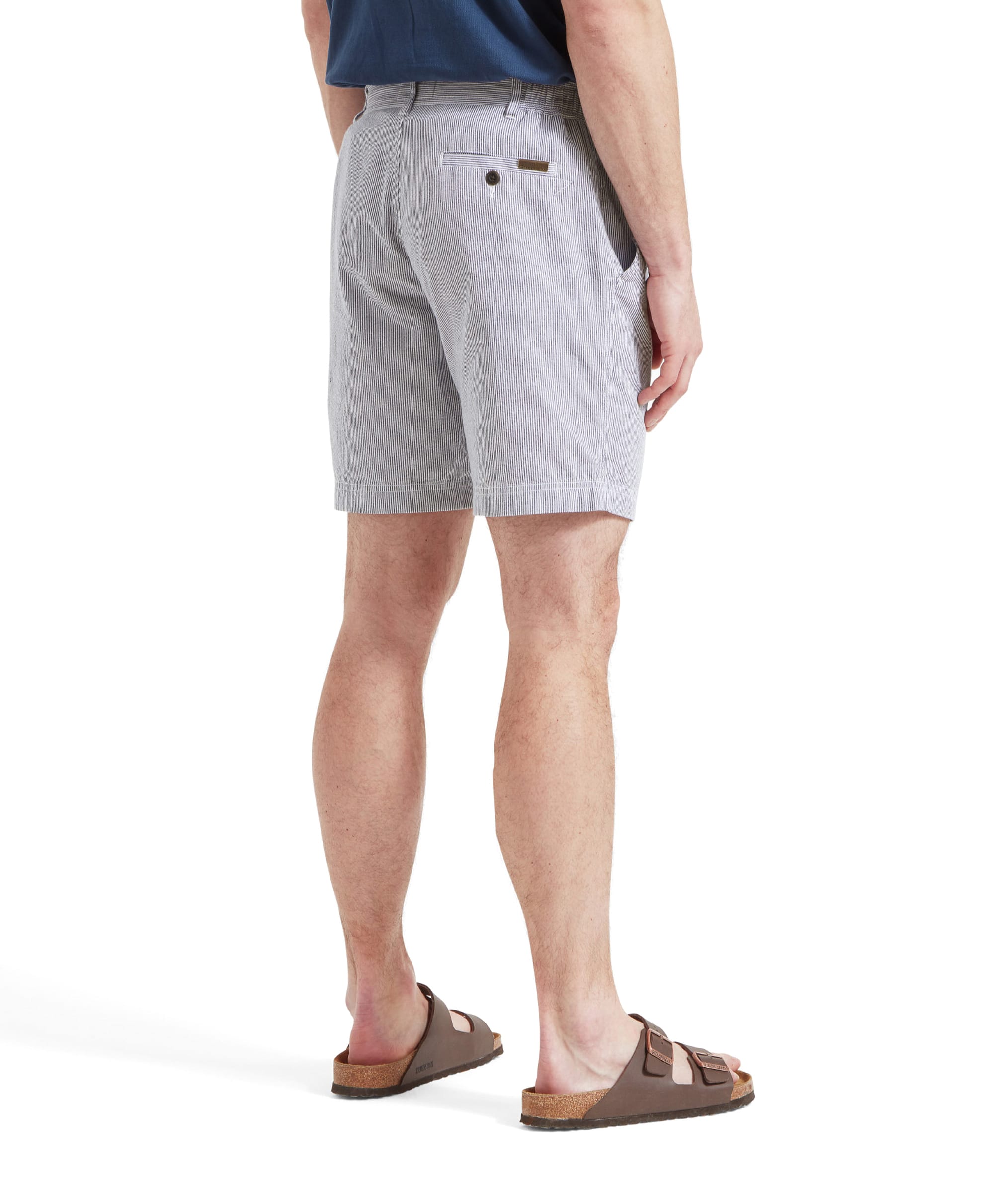 A back view of a man wearing the Schöffel Abersoch Shorts for Men in Navy, showing the back pocket details. He is also wearing a blue shirt and brown sandals.