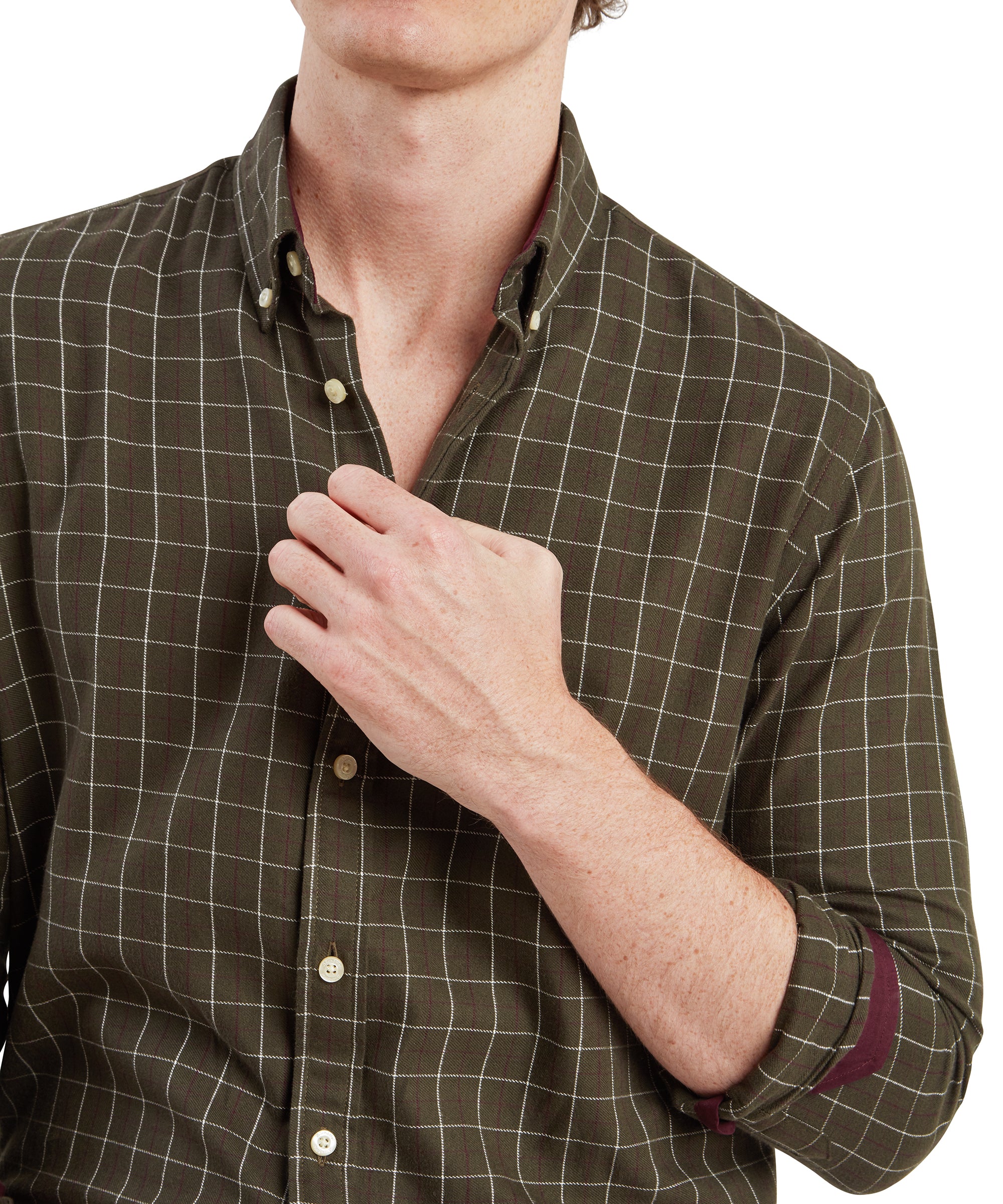 A close-up shot of the man’s torso, highlighting the Schöffel Aldeburgh Tailored Shirt for Men in Green. The man is holding the shirt’s collar with one hand, revealing the maroon lining inside the cuffs. The shirt is buttoned up, emphasising its neat and structured look.