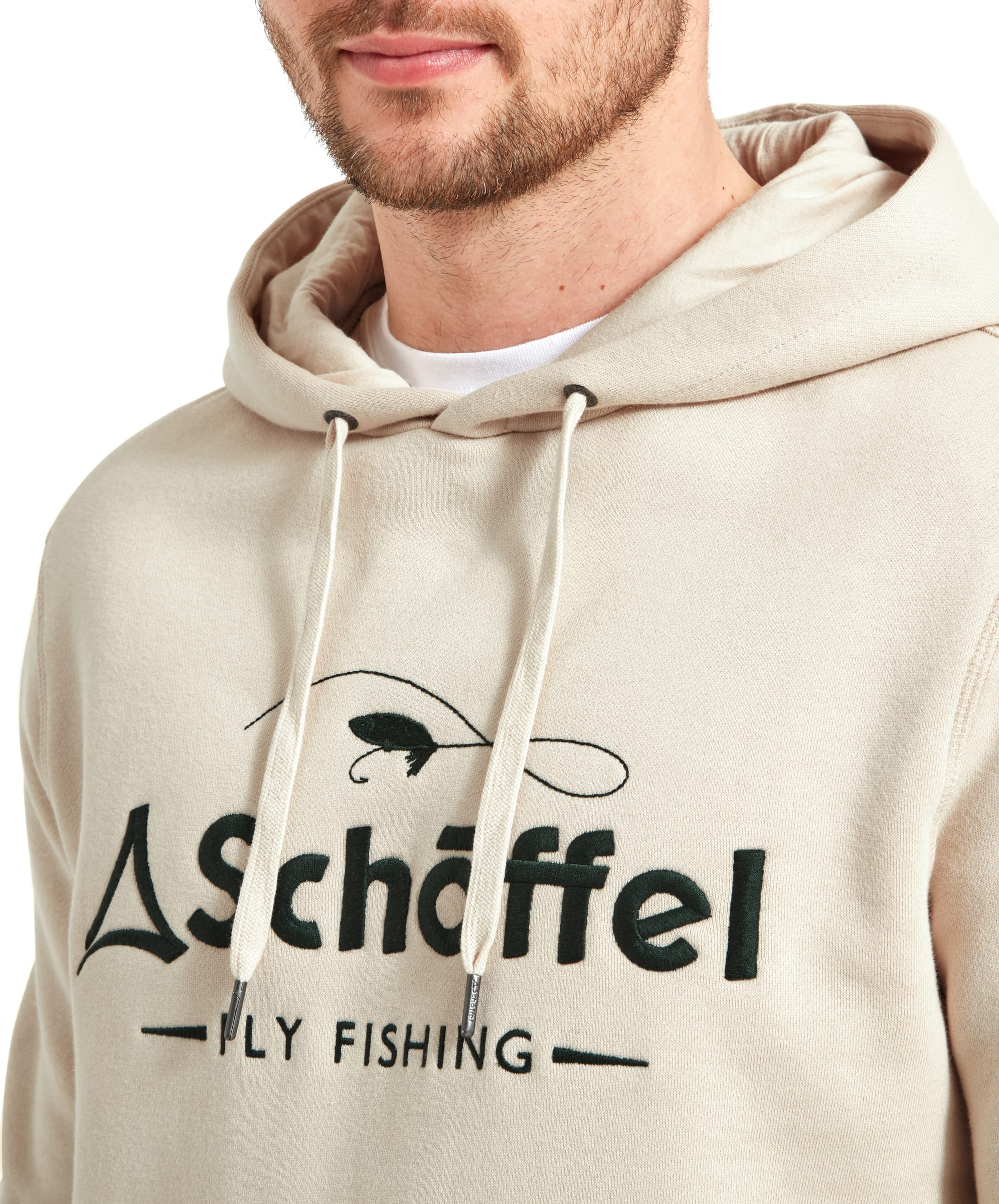 A close-up shot of a man wearing a Schöffel Alness Hoodie for Men in Light Brown, focusing on the "Schöffel Fly Fishing" logo on the front and the drawstrings of the hood.