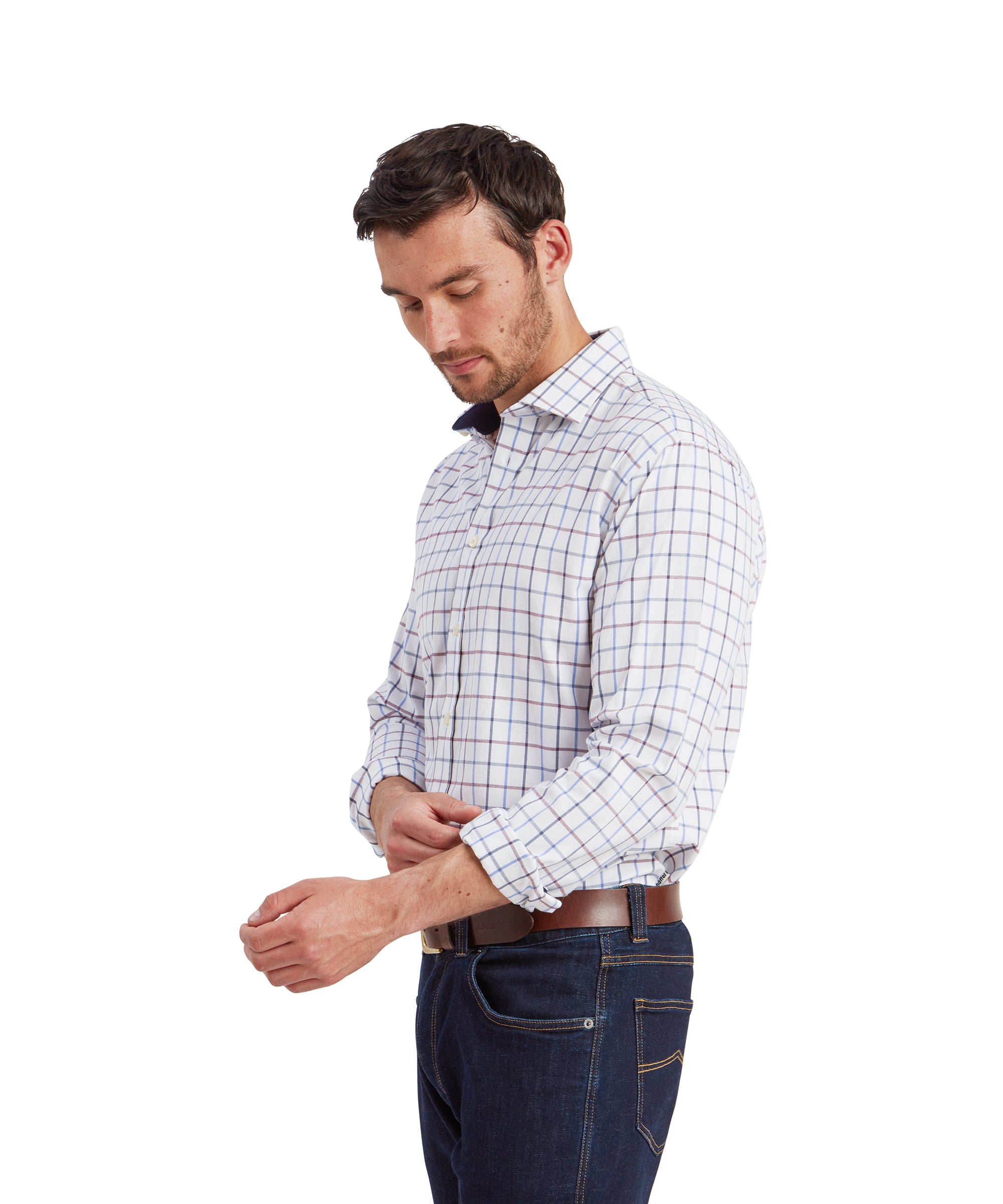 A side profile shot of the man adjusting the cuff of his Schöffel Baconsthorpe Tailored Shirt for Men in Navy and Yellow. The checkered pattern of the shirt is clearly visible, with his face slightly turned downward as he focuses on the cuff.