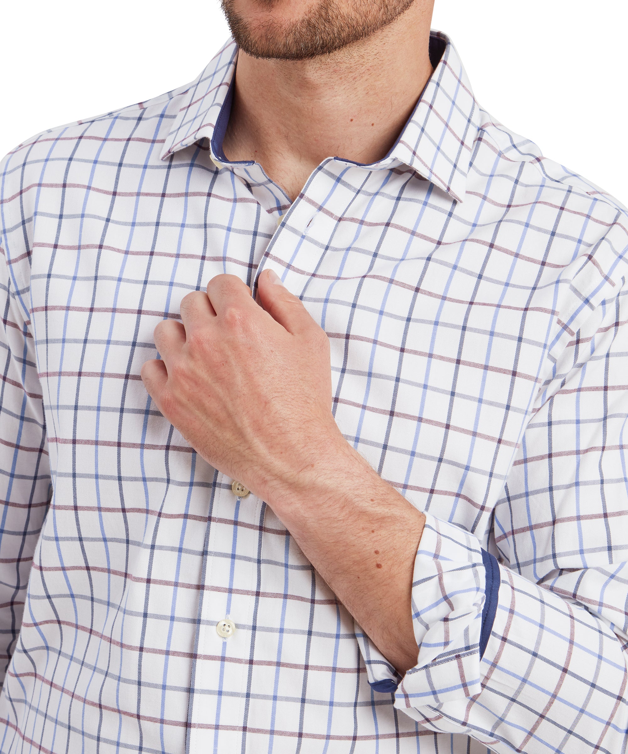 A close-up of the man’s upper torso and hands. He is slightly pulling at the collar of his Schöffel Baconsthorpe Tailored Shirt for Men in Navy and Yellow with his right hand. The checkered pattern of the shirt is detailed, and the buttons are visible, highlighting the crispness of the fabric.