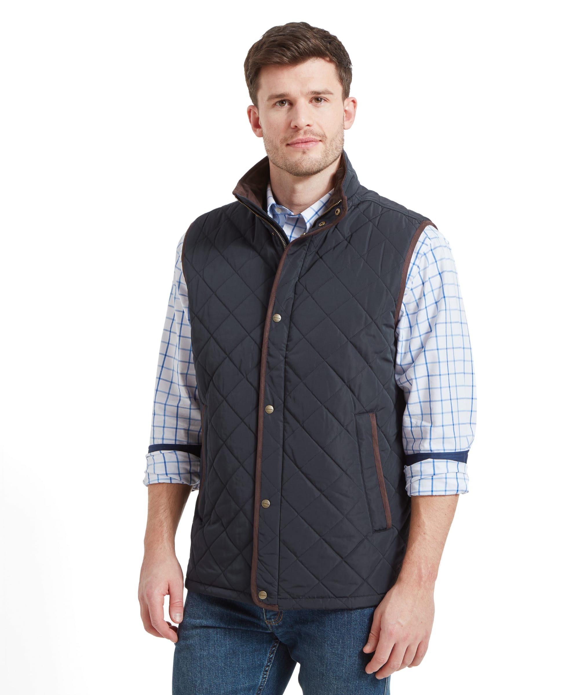 A man wearing a Schöffel Barrowden Quilt Gilet for Men in Blue with brown trim over a light blue and white checkered shirt. He is looking straight ahead with a slight smile.