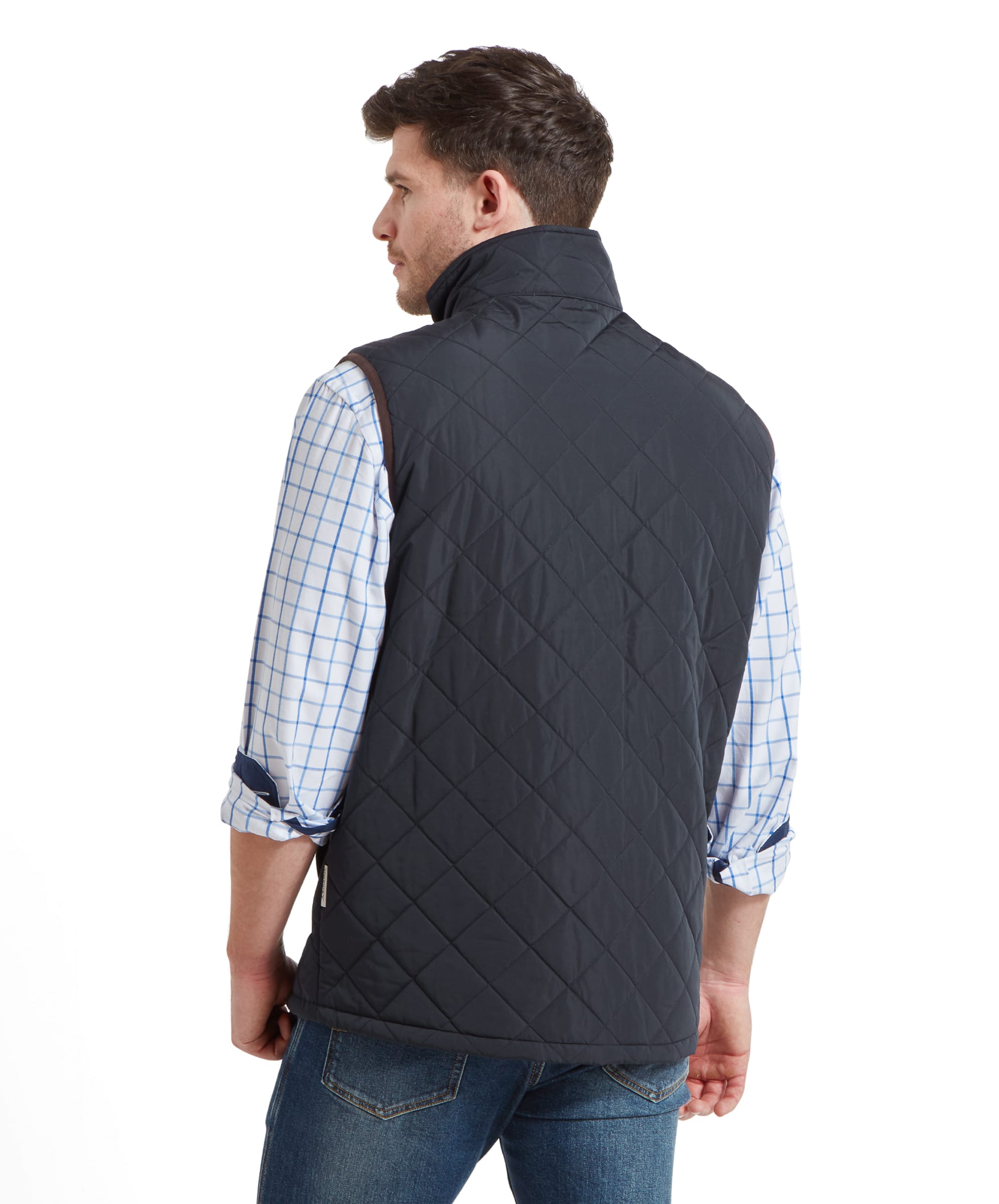 A back view of a man wearing a Schöffel Barrowden Quilt Gilet for Men in Blue with brown trim over a light blue and white checkered shirt, showing the quilted pattern on the back.