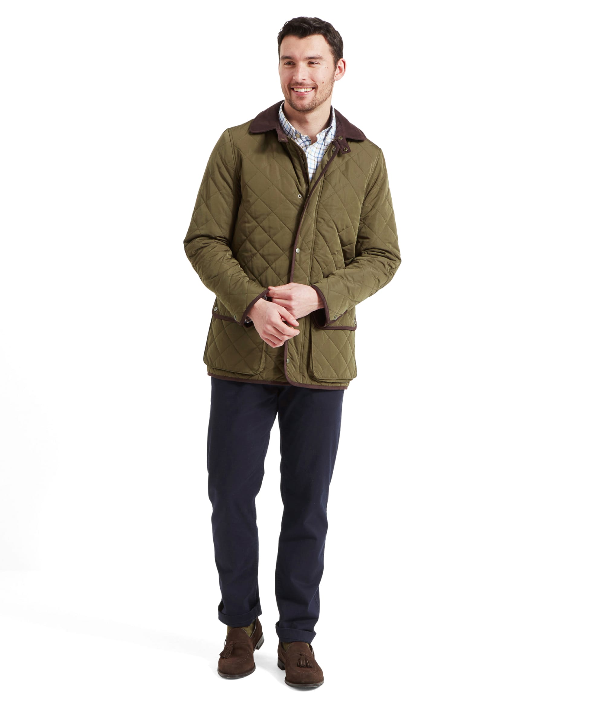 Full-body view of the man wearing the Schöffel Barrowden Quilt Jacket for Men in Green, paired with dark trousers and brown shoes, smiling while walking.