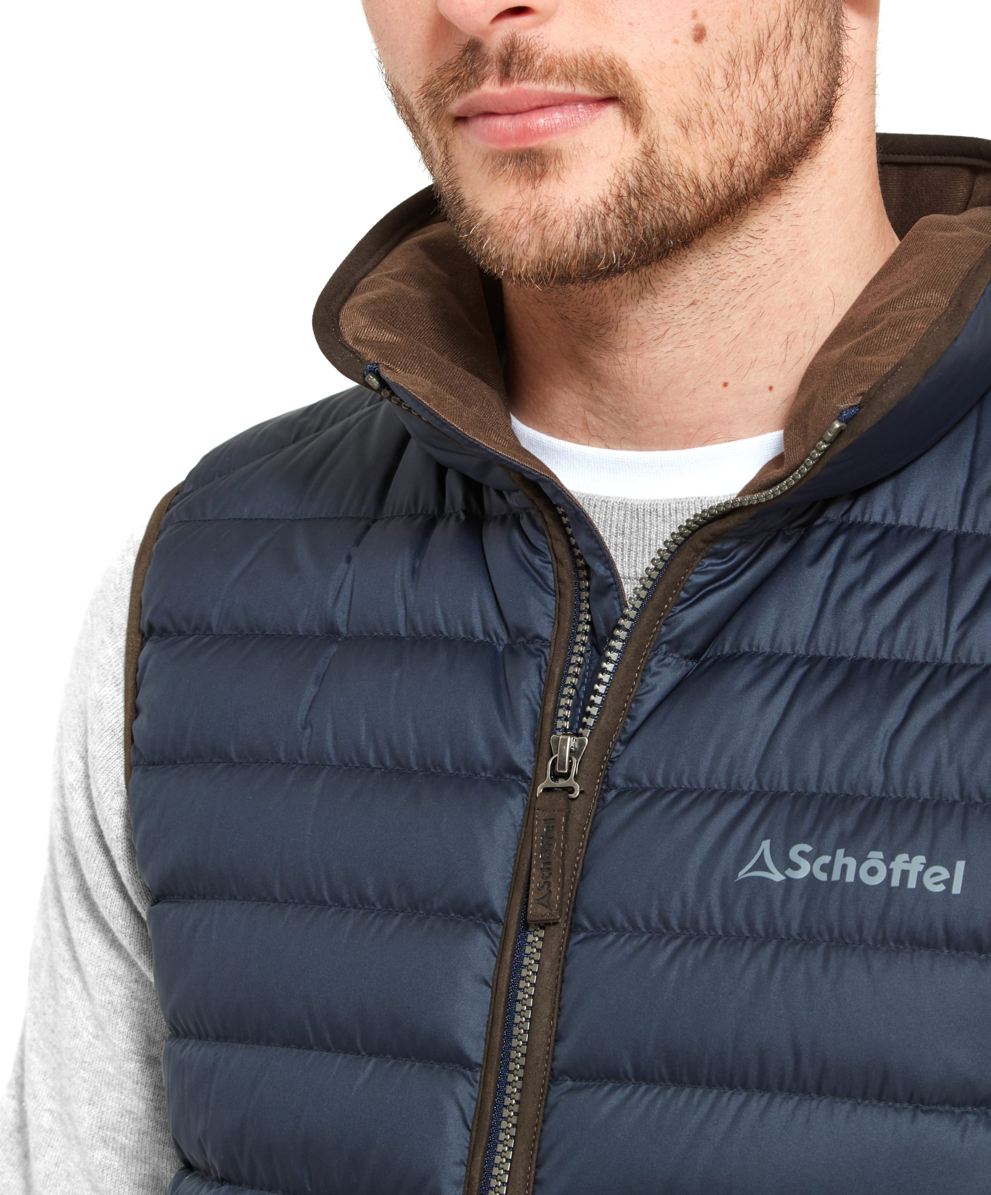 Close-up of a man’s face and upper chest, wearing a Schöffel Bowden Down Gilet for Men in Blue with a brown inner collar and visible zipper details.