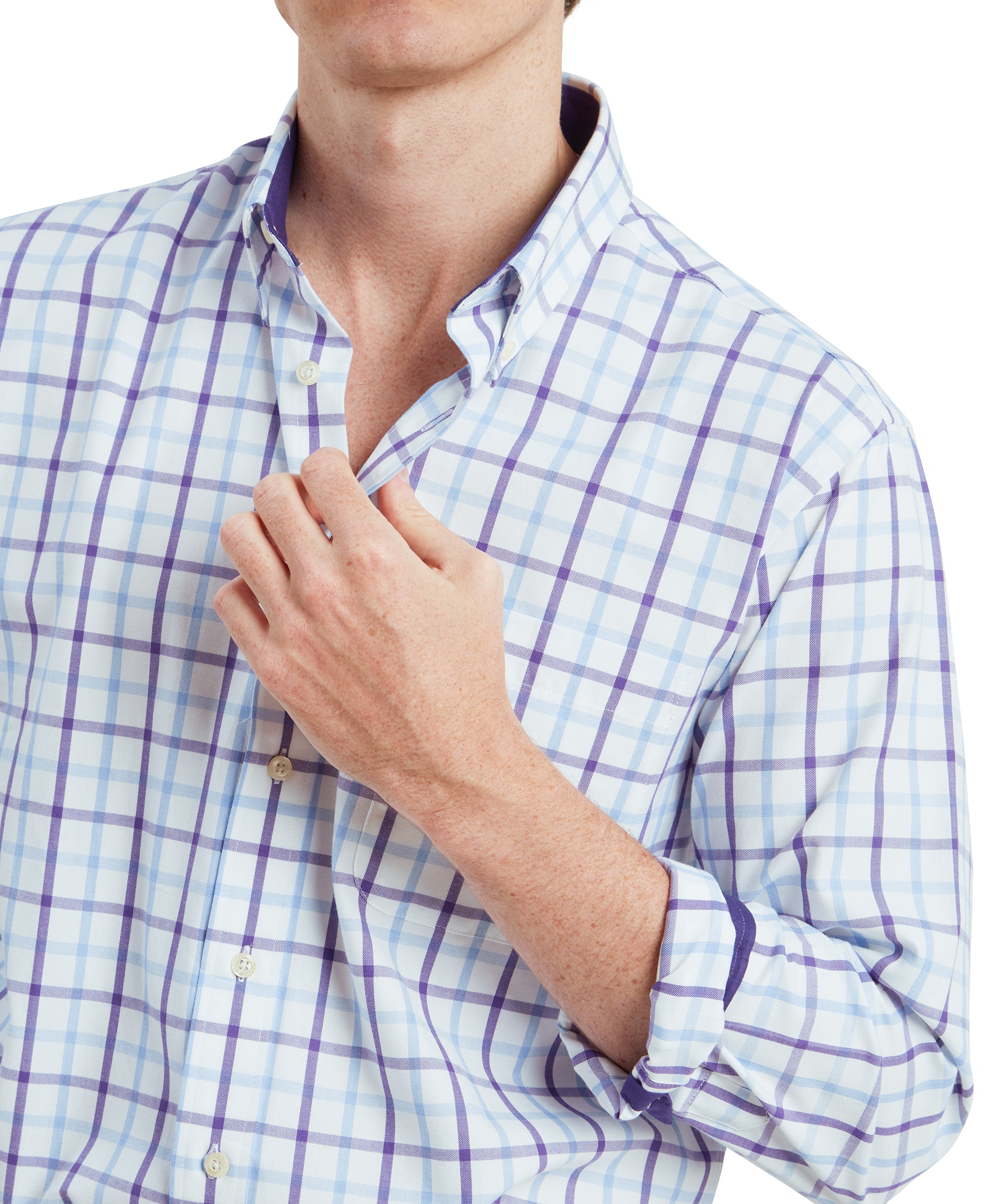 A close-up of the Schöffel Brancaster Classic Shirt for Men in Purple. The focus is on the collar and upper chest area, with the man holding the collar slightly open. The shirt’s pattern is clearly visible, with blue and purple lines intersecting to form a classic checkered design. The sleeves are rolled up, revealing a solid purple contrast on the inner cuff.