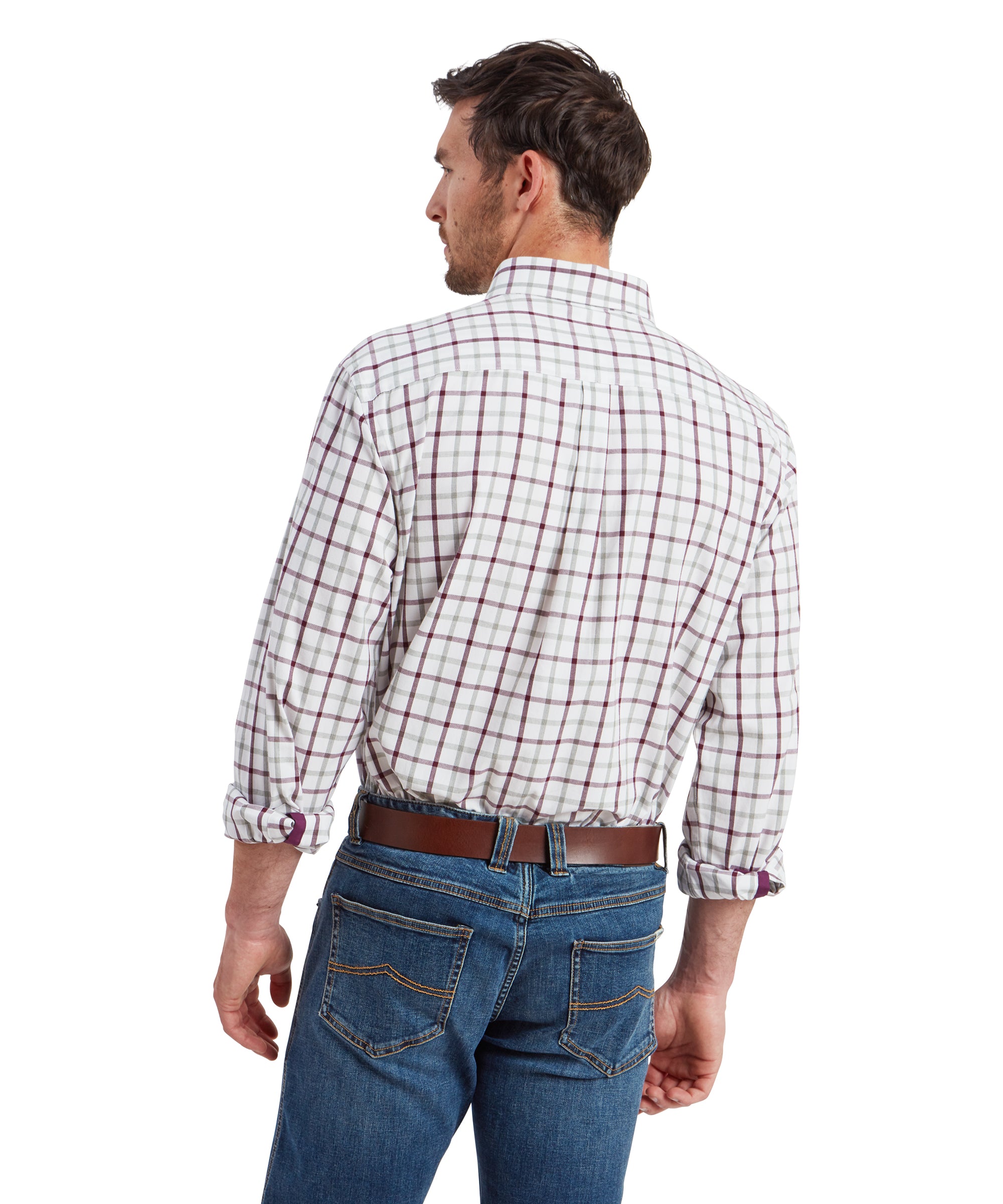 A back view of the man, highlighting the back details of the Schöffel Brancaster Classic Shirt for Men in Red and jeans. The shirt is neatly tucked in, showing the back yoke and pleat, and the jeans have visible stitching on the pockets. The brown leather belt complements the overall look, and the sleeves remain rolled up.