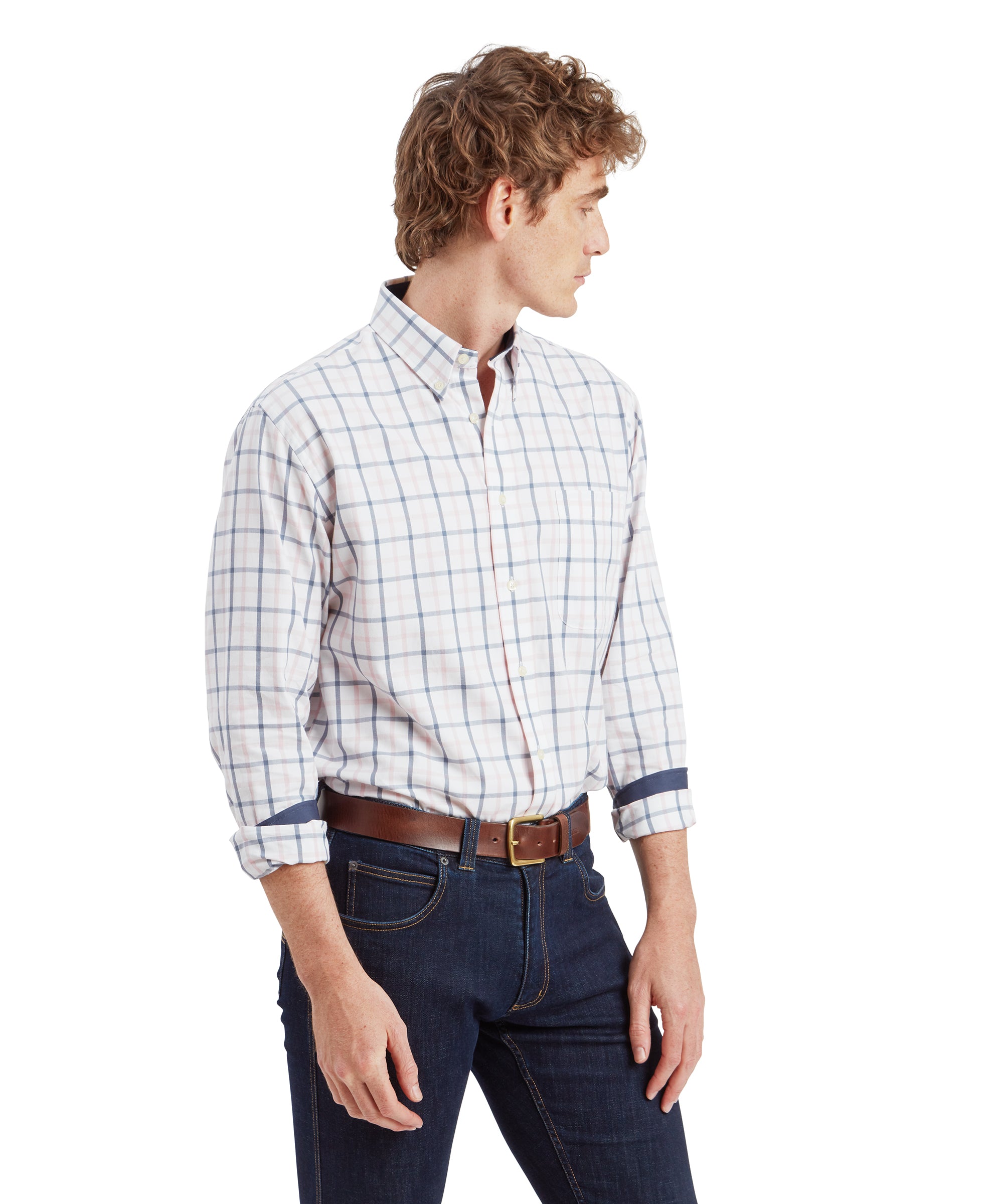 A side profile of the man wearing the same outfit. He is standing with his arms relaxed, looking to the left. The Schöffel Brancaster Classic Shirt for Men in Blue is clearly visible, as are the details of his brown leather belt.