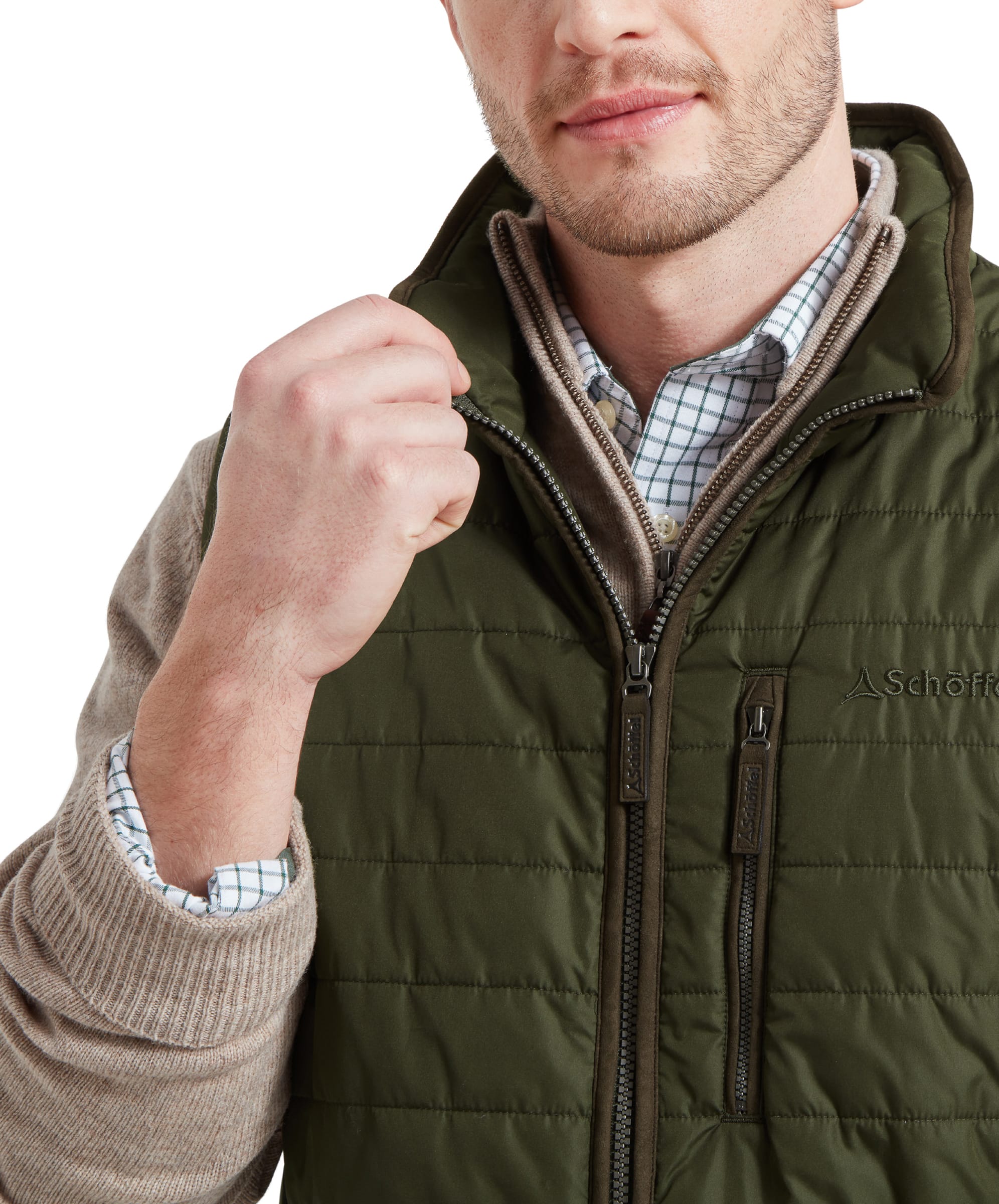 Close-up of the model adjusting the zipper of the Schöffel Brora Gilet for Men in Green, showing details of the high collar and checked shirt underneath.