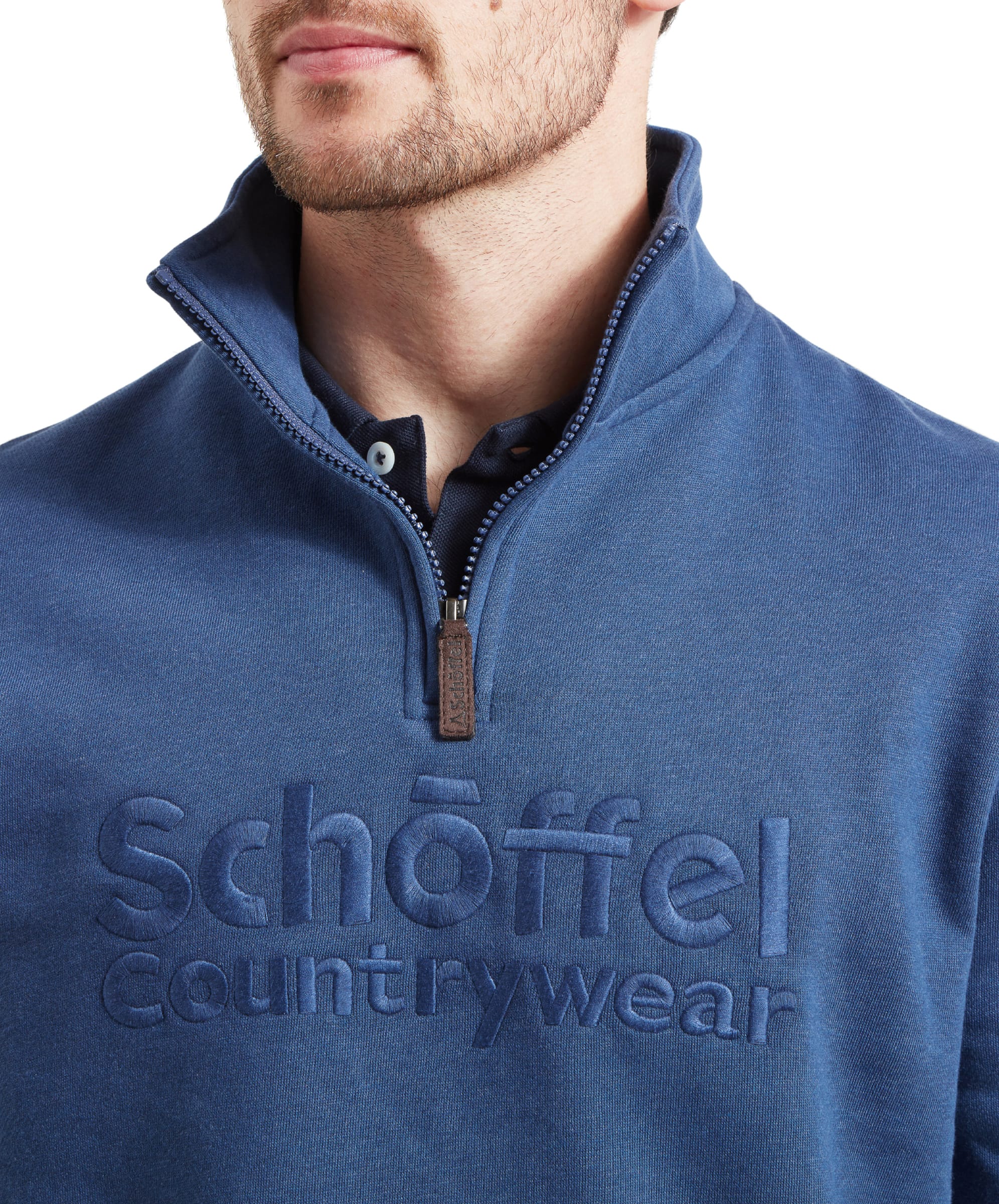 Close-up of the Schöffel logo embroidered on the front of the Schöffel Bude Sweatshirt for Men in Blue, with the man's face partially visible.