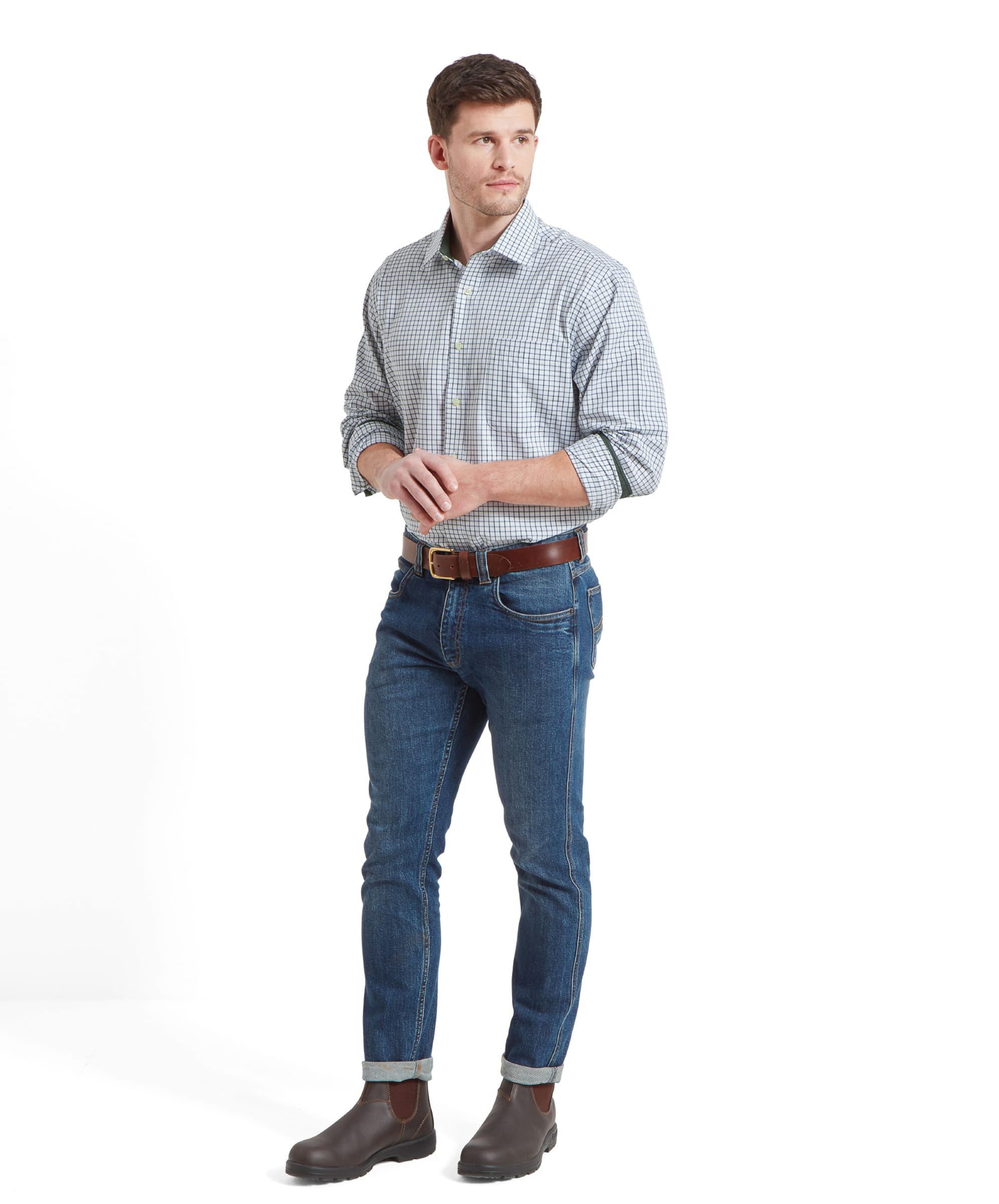 Full-body shot of the man wearing the Schöffel Cambridge Classic Shirt for Men in Green, paired with jeans and brown boots, standing and looking to his right.