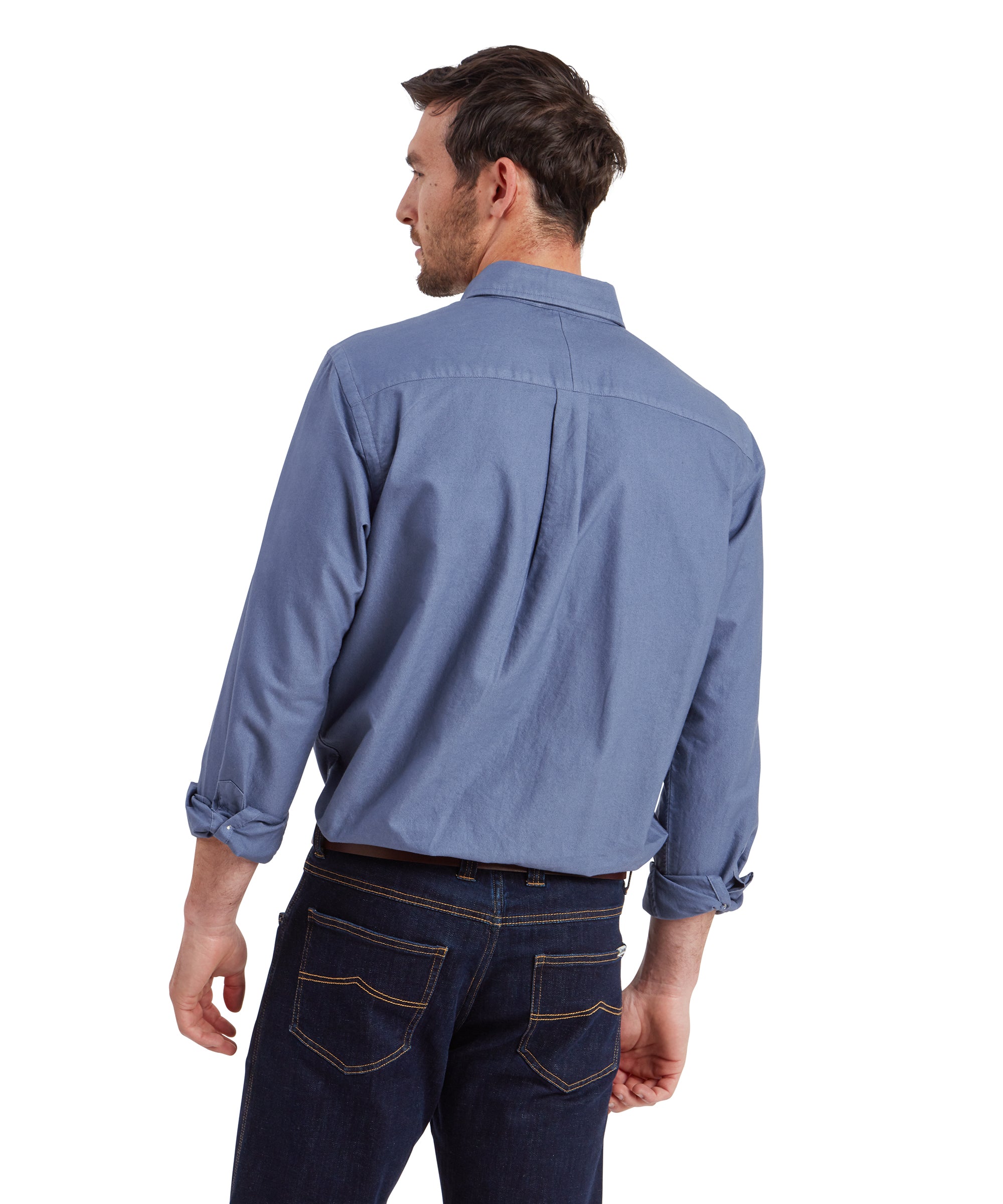 A back view of the man showing the rear of his Schöffel Cavendish Oxford Shirt for Men in Navy. The shirt is neatly tucked into his dark jeans, and the yoke of the shirt is clearly visible, showing how the fabric drapes naturally over his back.