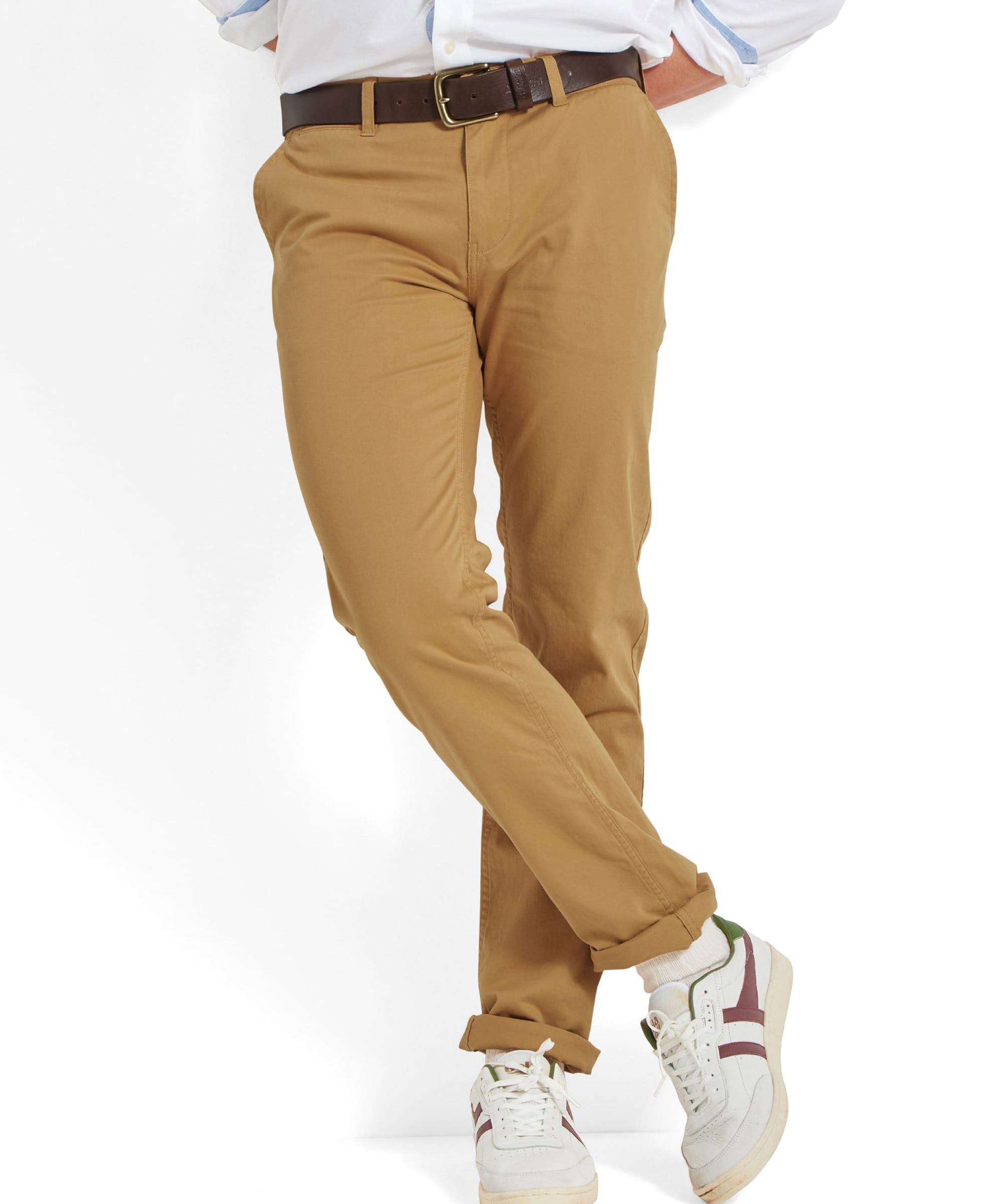 Full-body view of the model in a relaxed pose, wearing the Schöffel Chichester Chino in yellow, paired with white trainers.