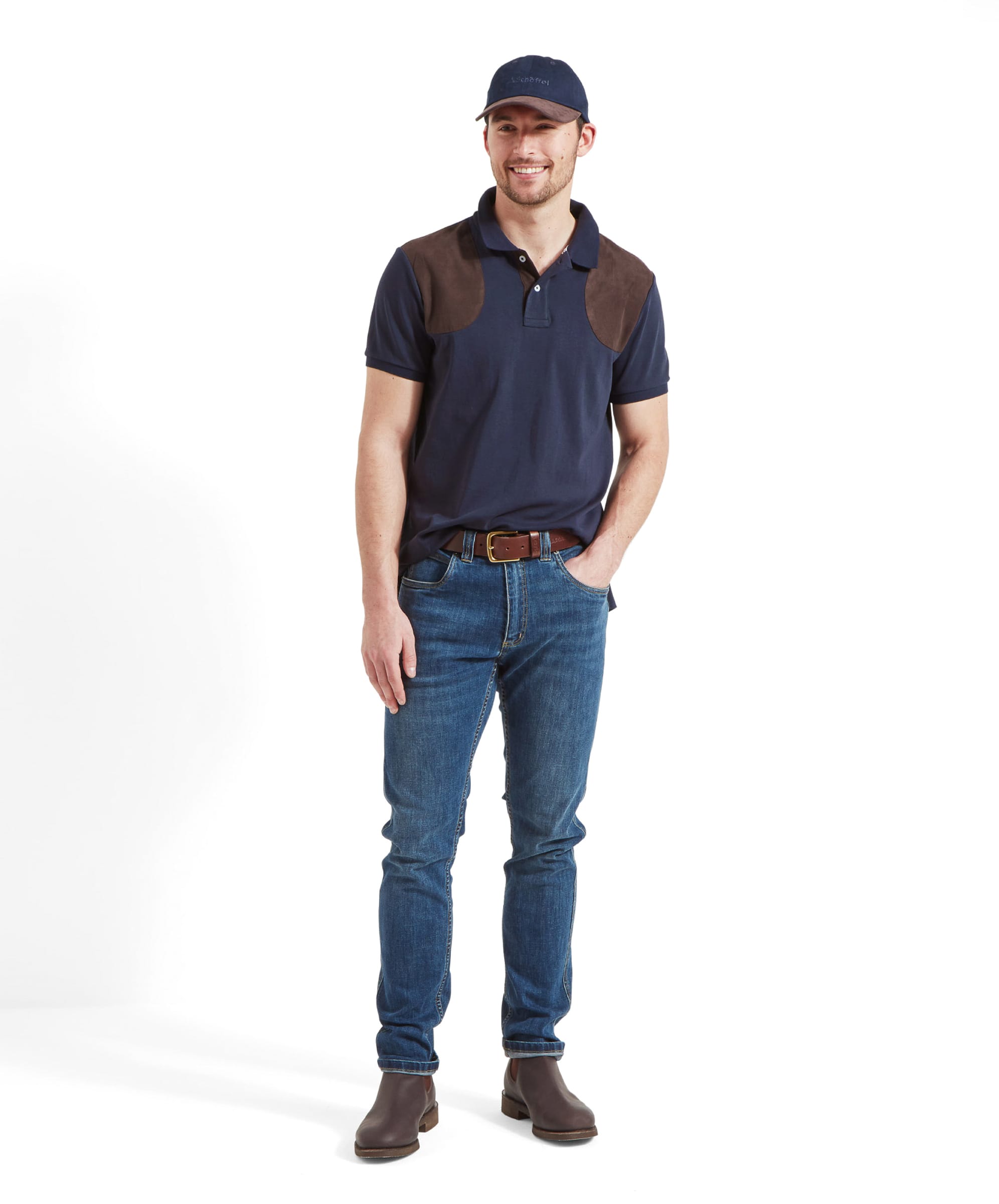 Full-body view of a man in a Schöffel Cordoba Polo Shirt for Men in Navy with brown shoulder patches, blue jeans, and brown shoes.