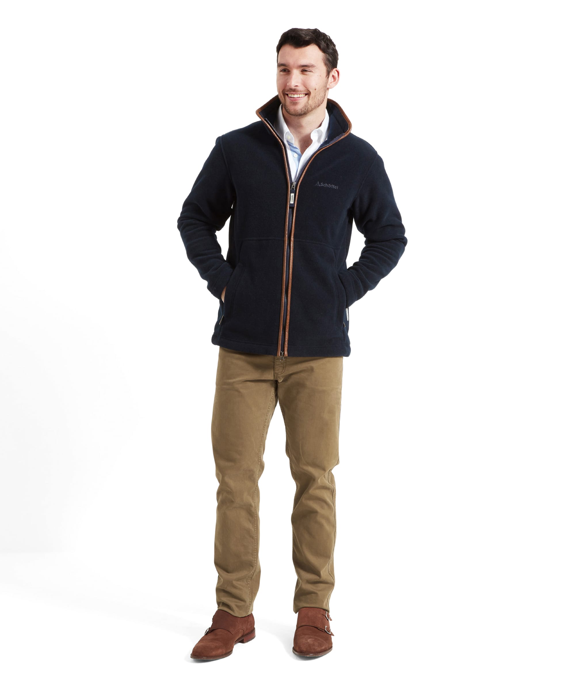 Full-body front view of a man in Schöffel Cottesmore Fleece Jacket for Men in Navy, with hands in pockets and dressed in khaki trousers and brown shoes.