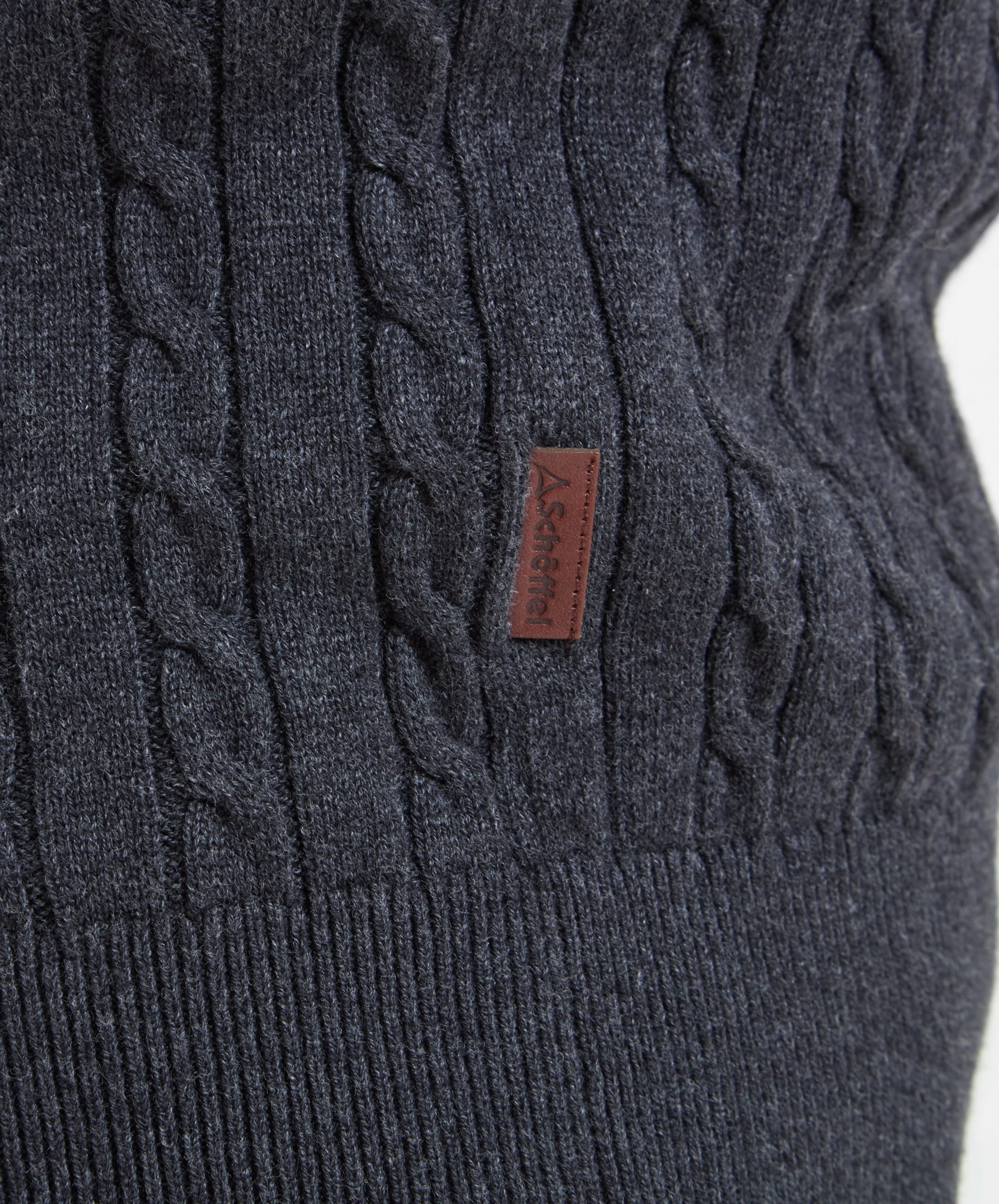 Close-up of the Schöffel logo tag on the Schöffel Cotton Cashmere Cable 1/4 Zip Jumper for Men in Grey.