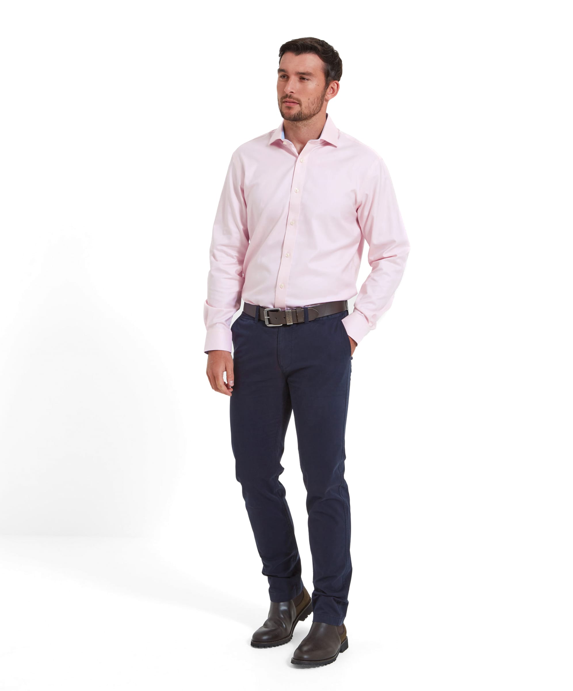 The full-body view of the model wearing the Schöffel Greenwich Tailored Shirt for Men in Pink, paired with navy trousers and brown shoes.