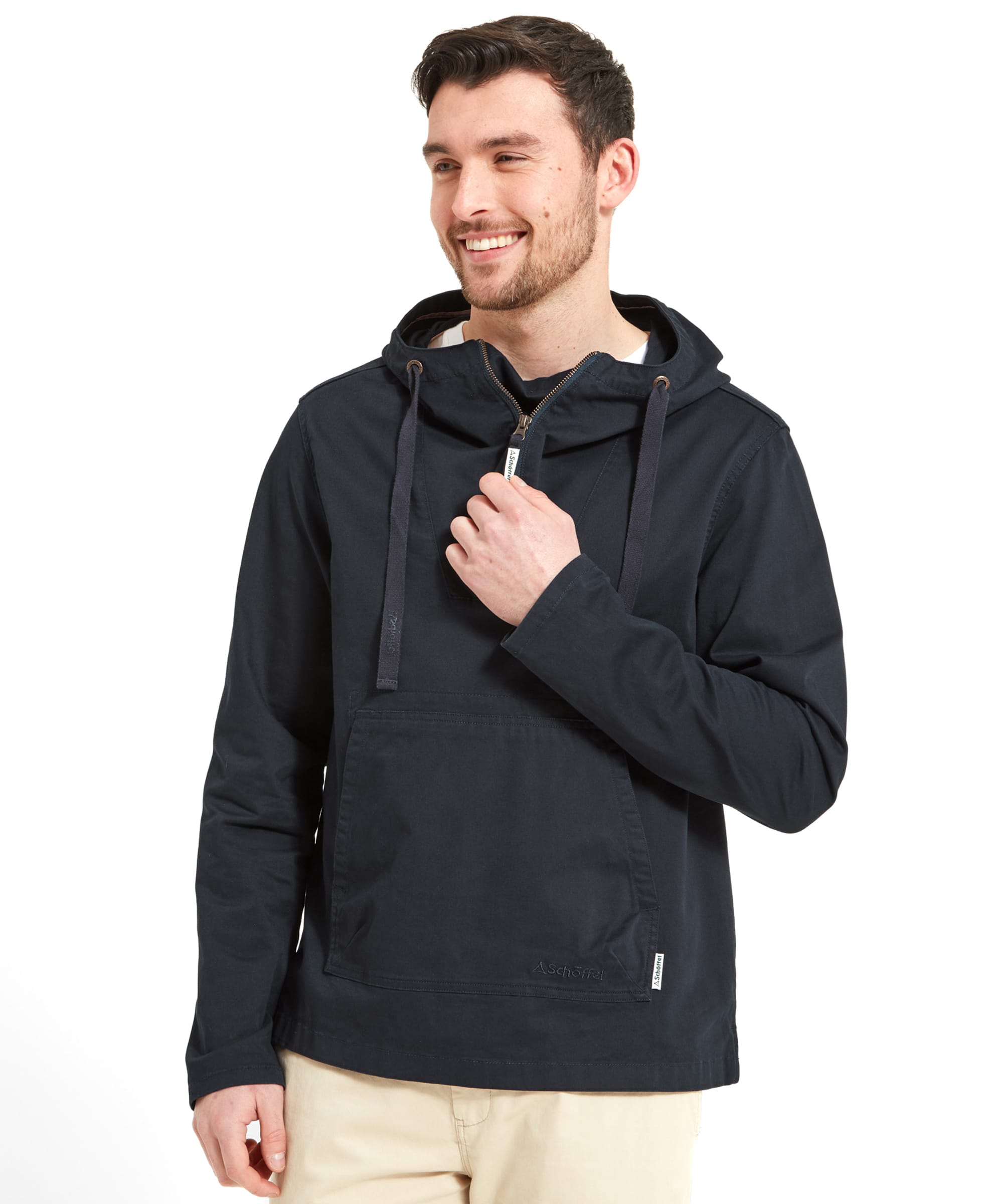 A model wears the Schöffel Harbour Smock for Men in Navy whilst looking to his left with a hand pulling the front zip.