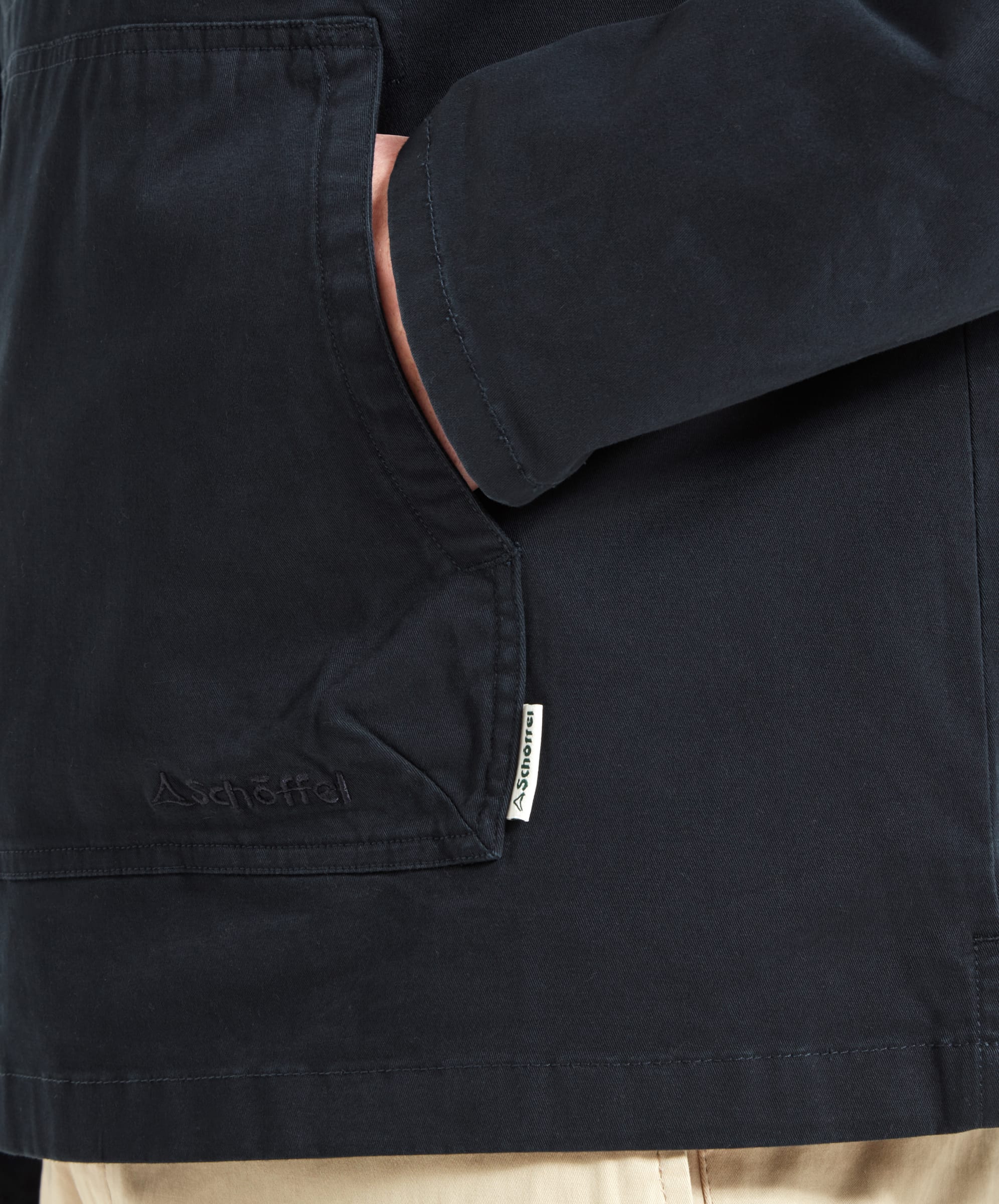 A close-up of the pocket on the Schöffel Harbour Smock for Men in Navy, highlighting the whIte brand tag down the seam.