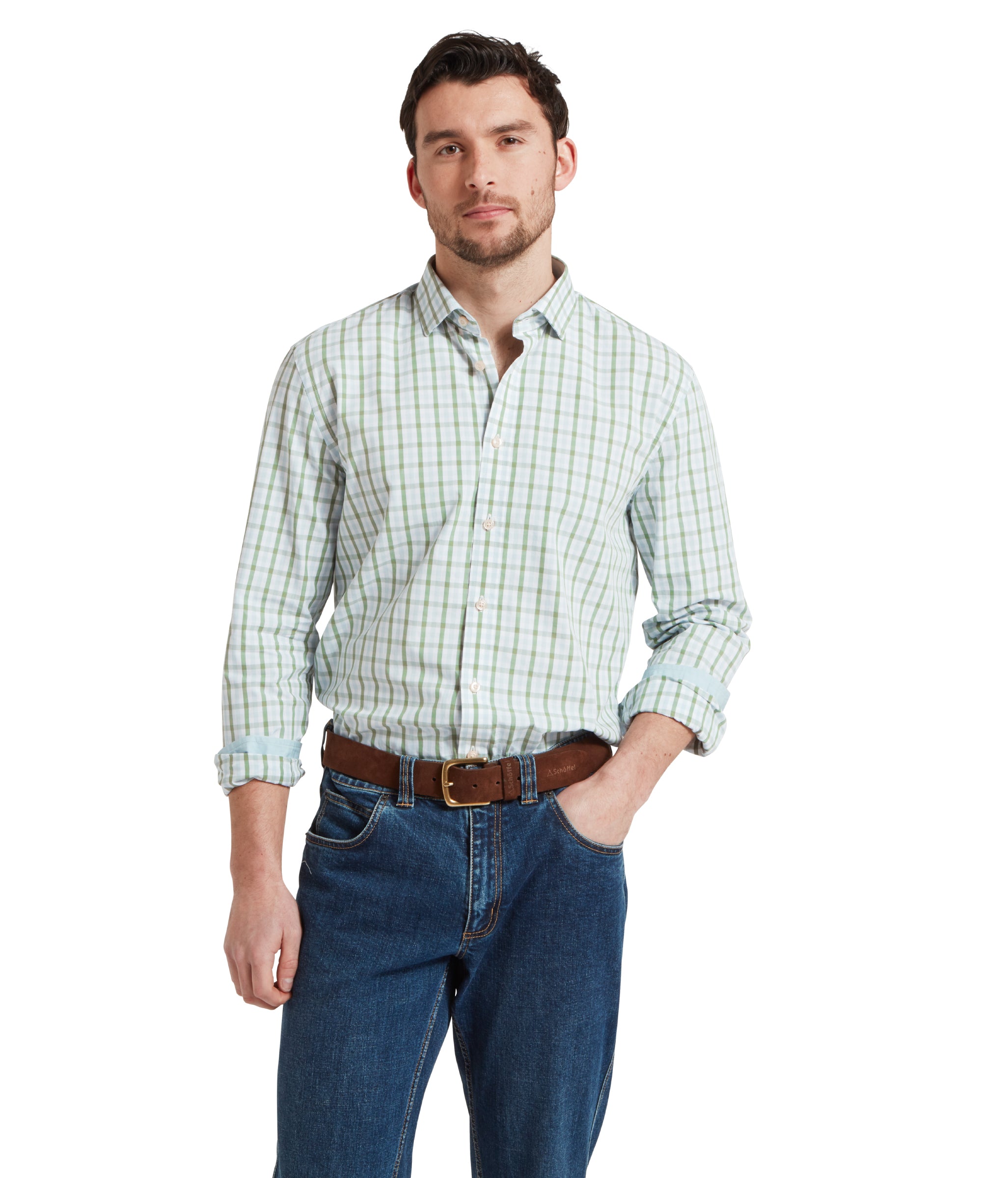 A man wears the Schöffel Hebden Tailored Shirt for Men in Green and Blue with navy jeans and a brown belt. The man is standing in a relaxed pose with one hand in his pocket.