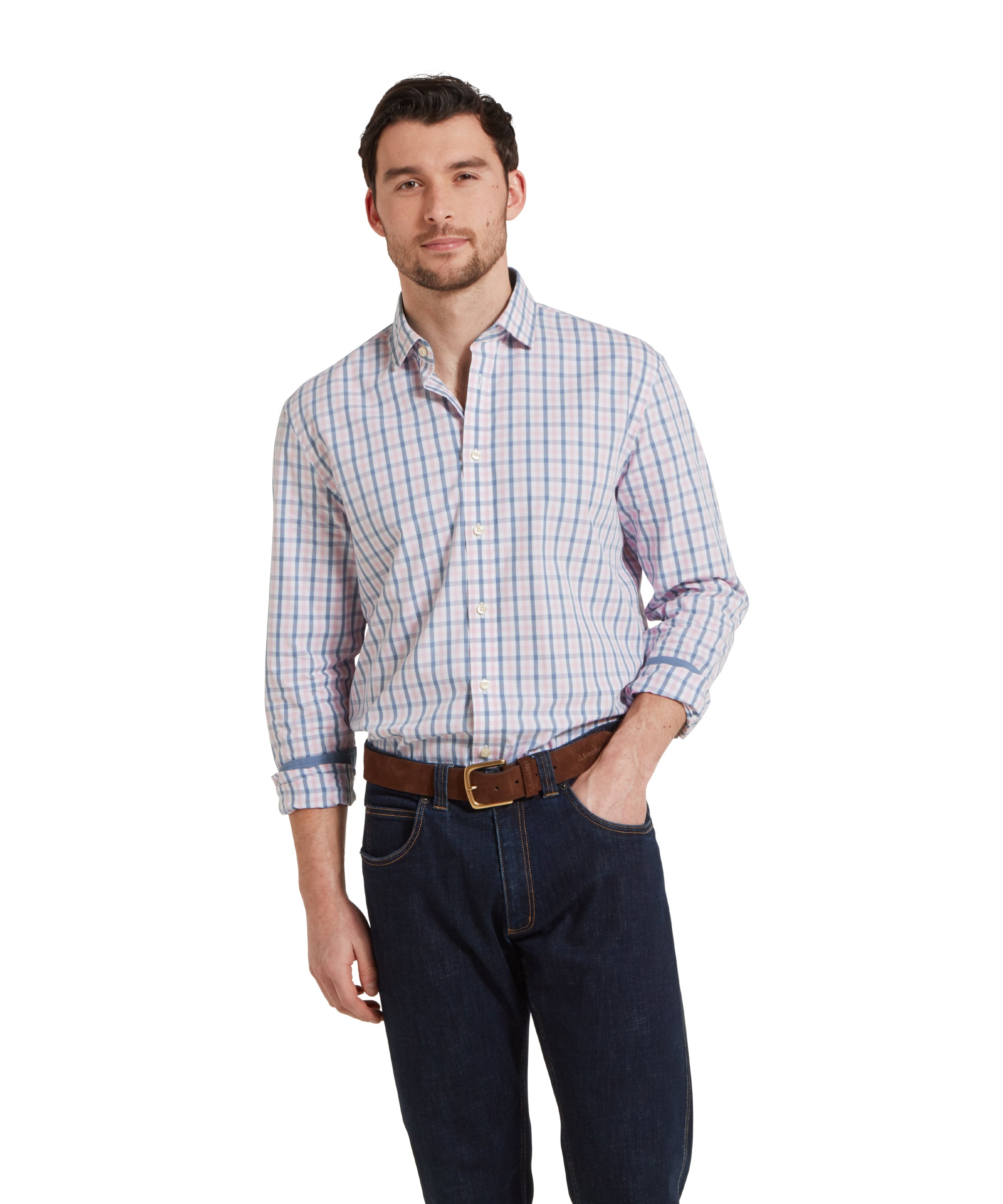 A man wears the Schöffel Hebden Tailored Shirt for Men in Dark Blue and Pink with dark navy jeans and a brown belt. The man is standing in a relaxed pose with one hand in his pocket.