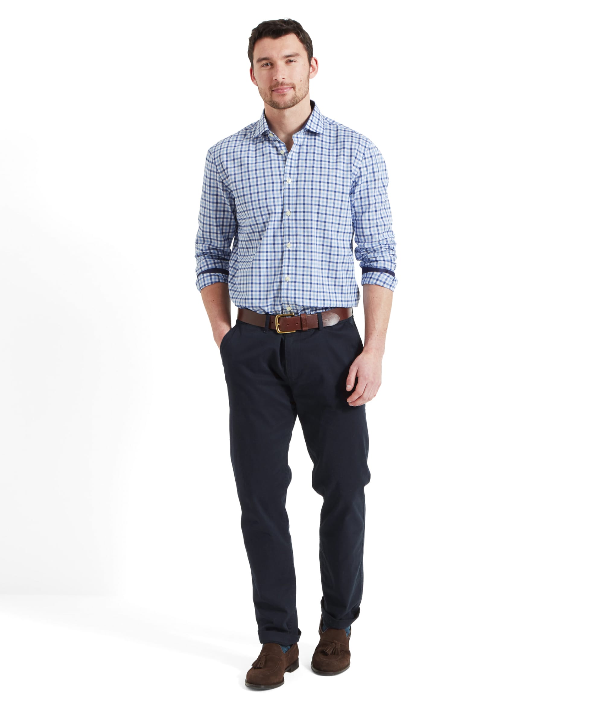 Full body view of a man wearing the same Schöffel Hebden Tailored Shirt for Men in Blue Navy with blue trousers, brown leather belt and brown suede loafers. He has his left hand in the trouser pocket and is smiling walking forward.