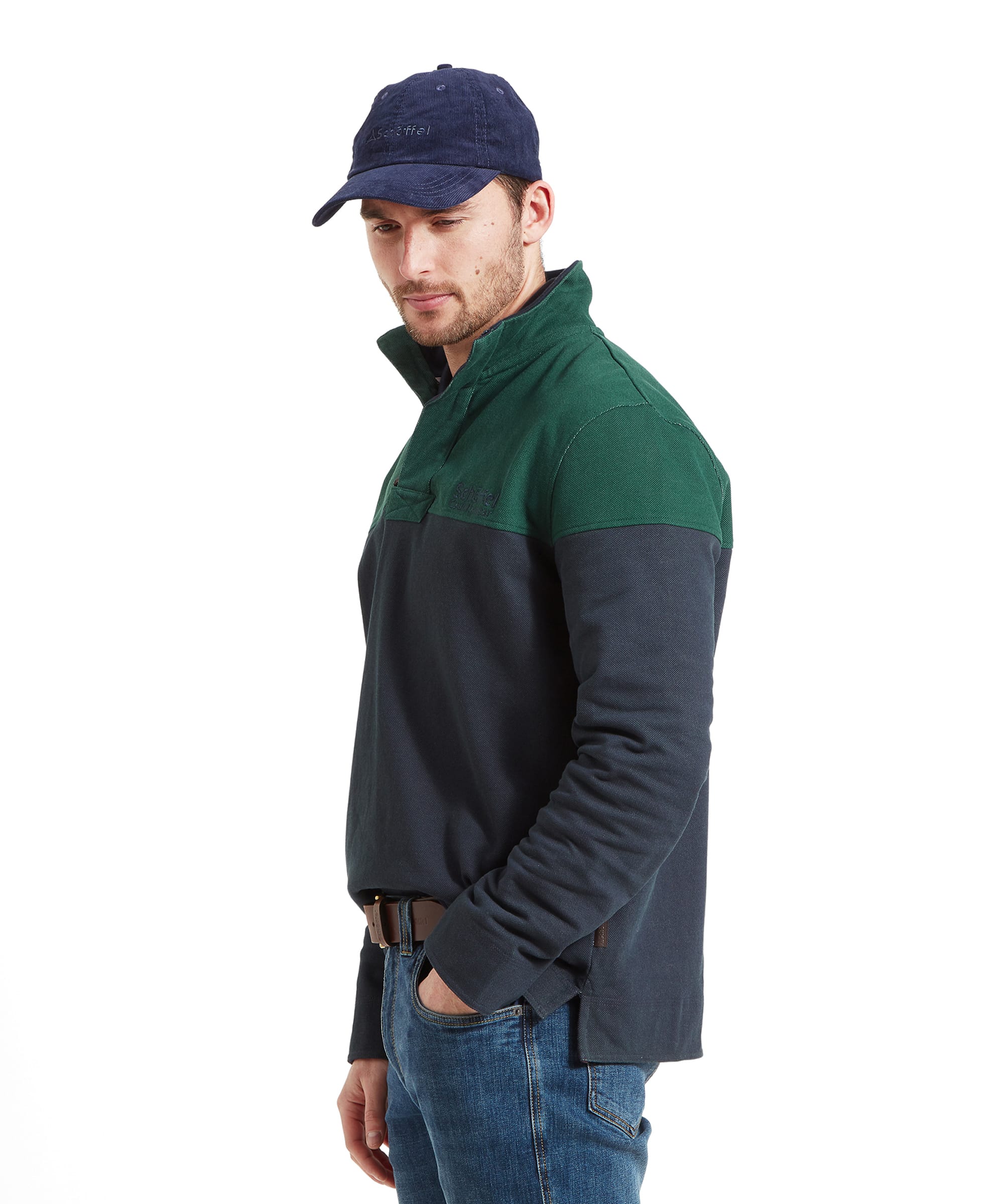 Side view of a man wearing the Schöffel Helford Heritage Sweatshirt for Men in Green with a blue cap looking down. He has his right hand his jeans pocket.