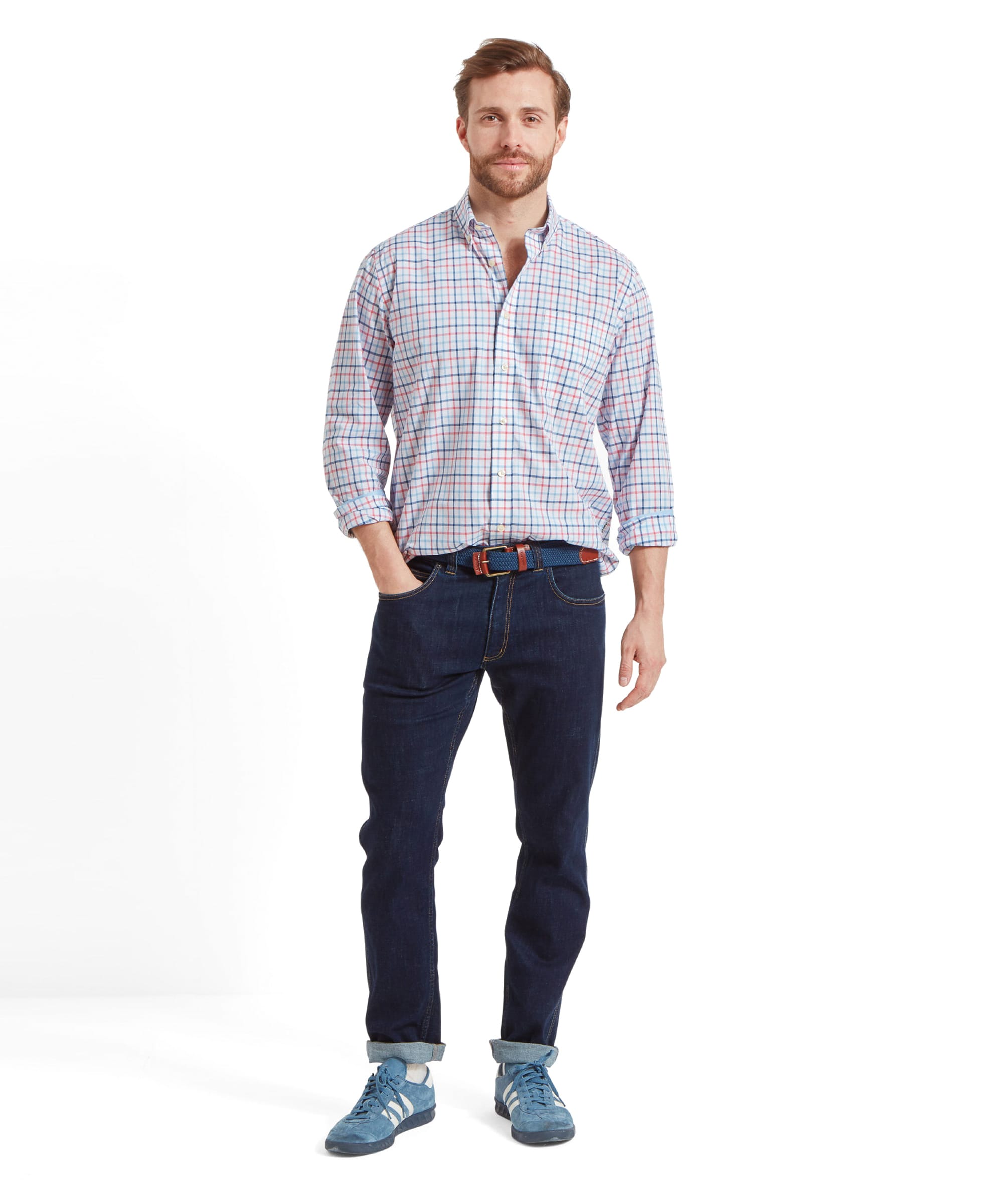 Full body view of the same man wearing the Schöffel Holkham Classic Shirt for Men in Navy and Red with his left hand in his pocket. He wears with dark navy jeans, a blue woven belt and light blue trainers