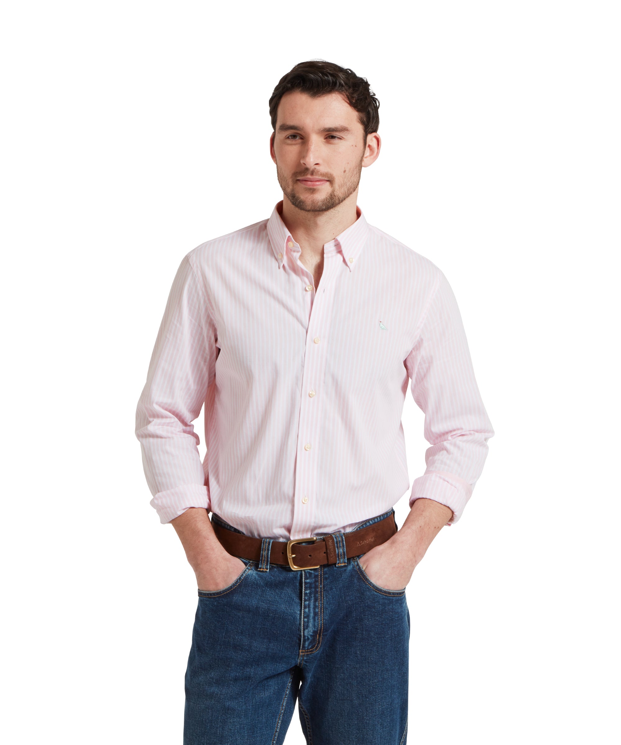 Close-up of a male model wearing a pink and white striped Schöffel shirt, paired with mid denim jeans and a tan leather belt. He is standing in a relaxed pose with his hands in his pockets.