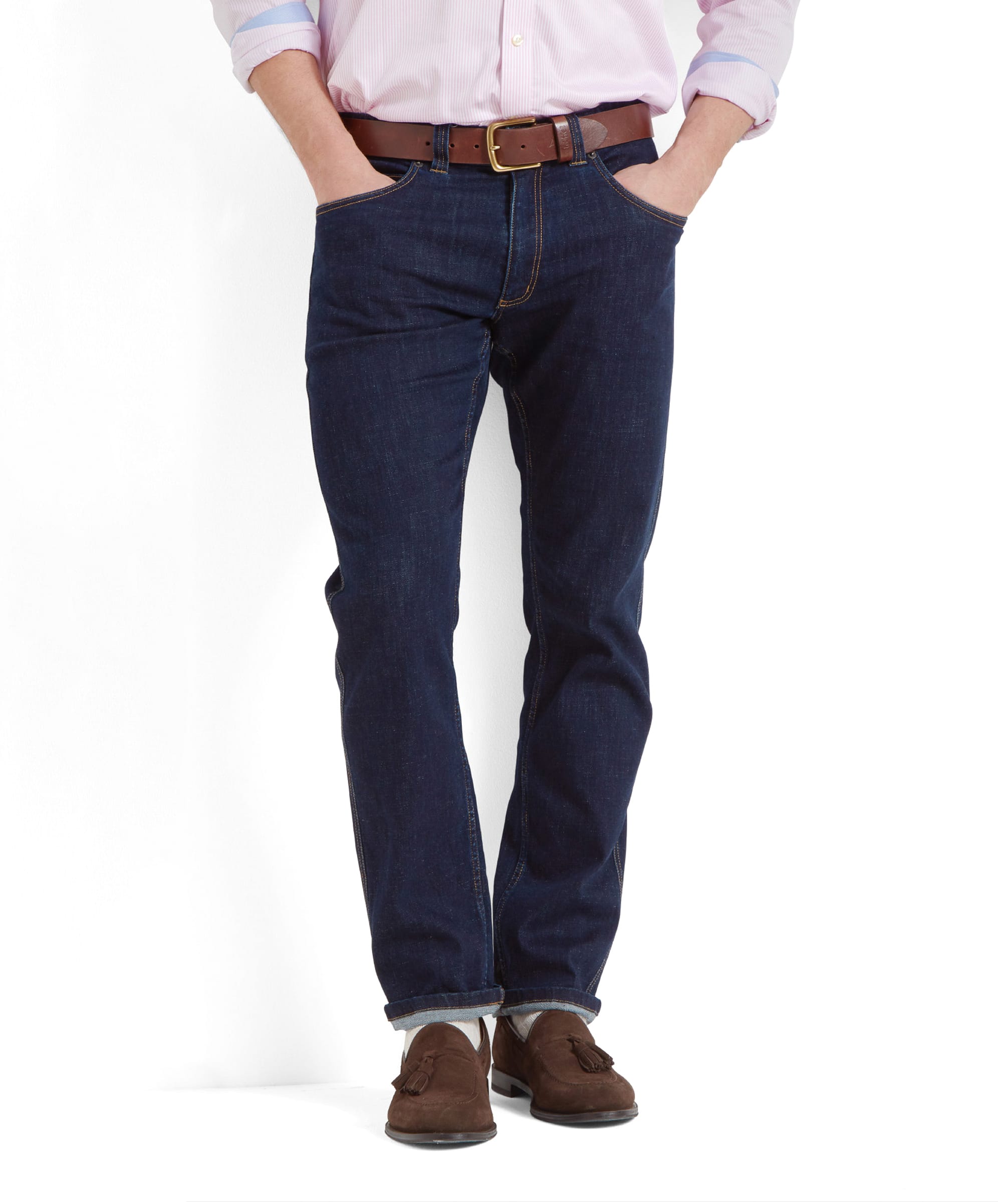 A man wears the Schöffel James Jean for Men in Navy with a brown leather belt and brown suede belts. The model holds his hands in the jeans pockets.