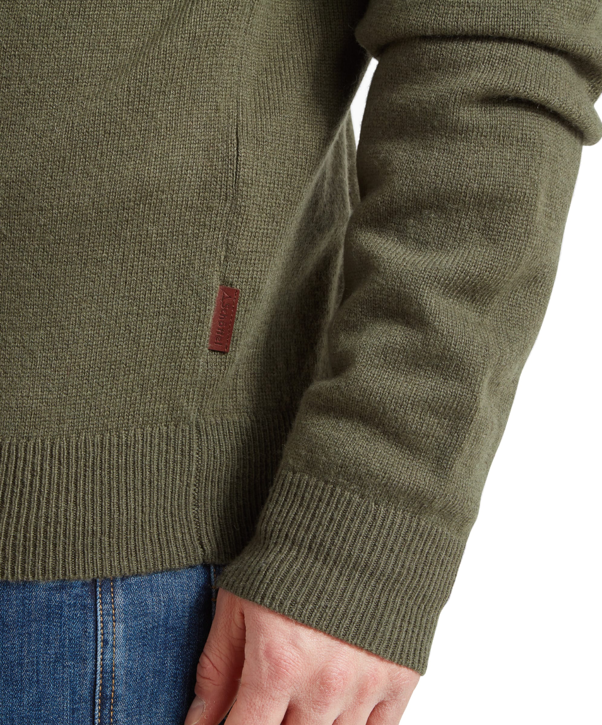 Close-up of the cuff area of the Schöffel Lambswool 1/4 Zip for Men in Green highlighting the fine ribbed cuff and the faux leather branded tab down the right side seam.