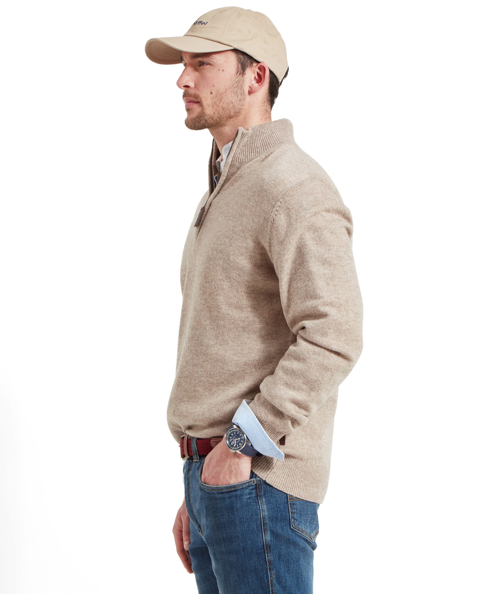 Side view of the Schöffel Lambswool 1/4 Zip for Men in Light Brown as the model looks to the side and his hand placed in his right pocket with a large blue watch.