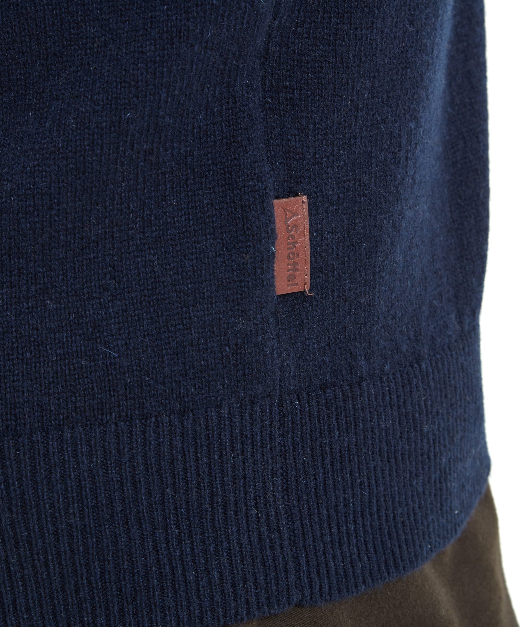 Close-up of the  faux leather branded tag on the Schöffel Lambswool 1/4 Zip for Men in Navy