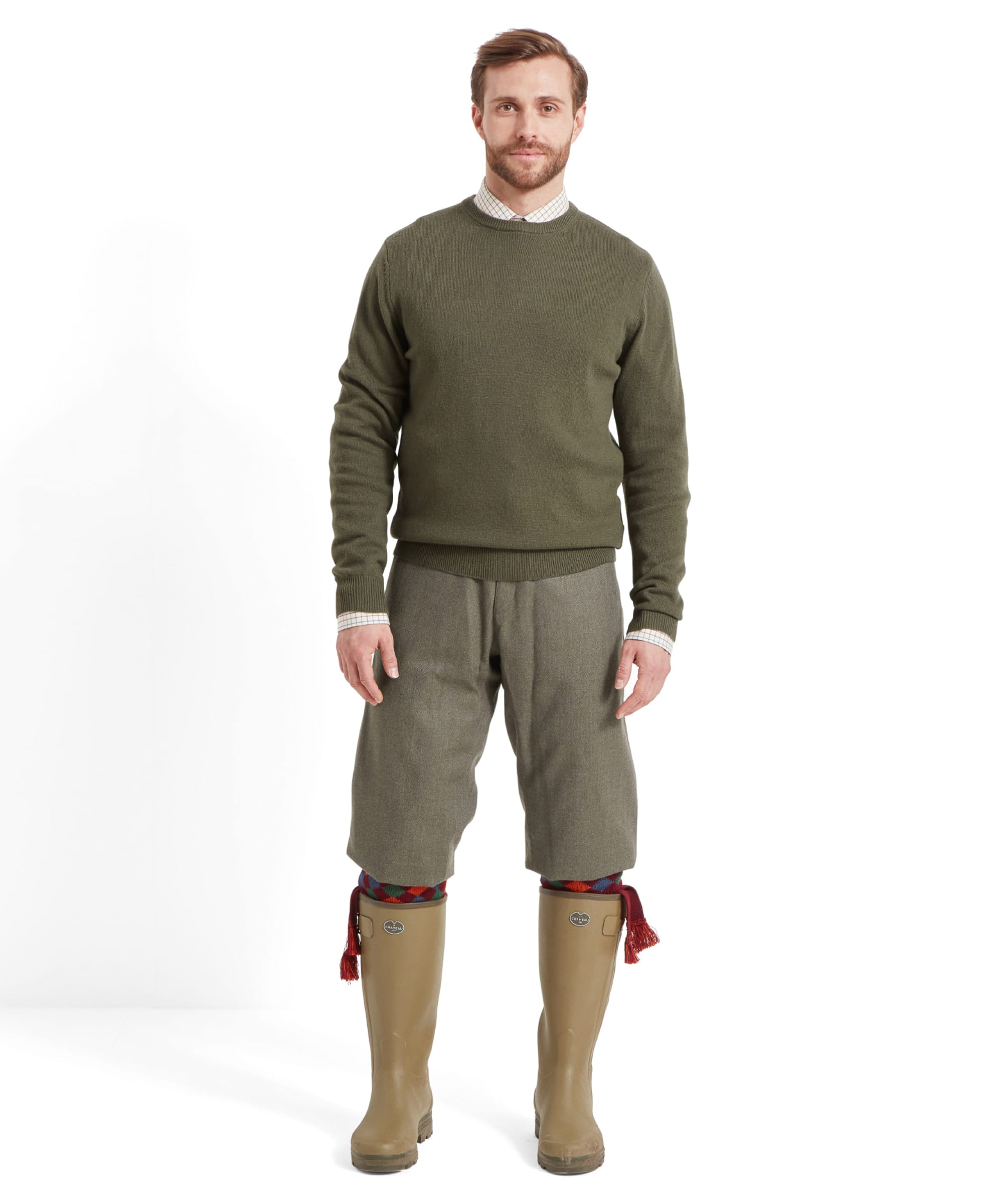 Full body shot of a man wearing the Schöffel Lambswool 1/4 Zip for Men in Green with a check shirt, tweed plus twos, wellington boots and tassled shooting socks.