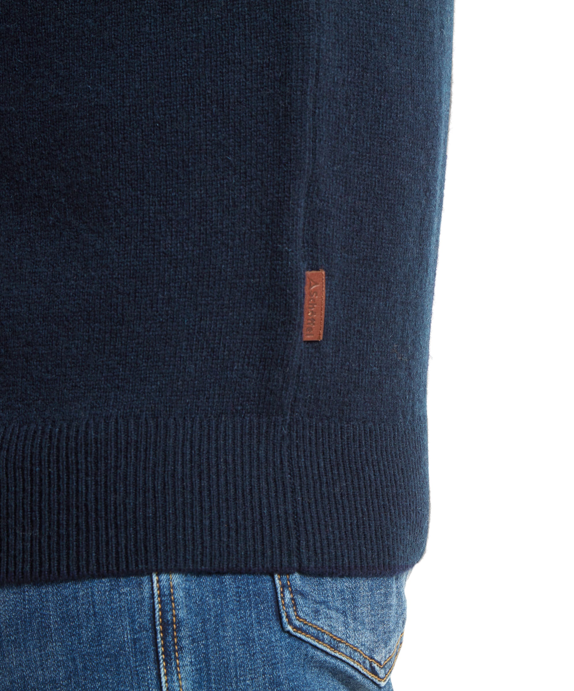 Close-up of the right side seam on the Schöffel Lambswool 1/4 Zip for Men in Navy highlighting the faux leather brown branded tag.