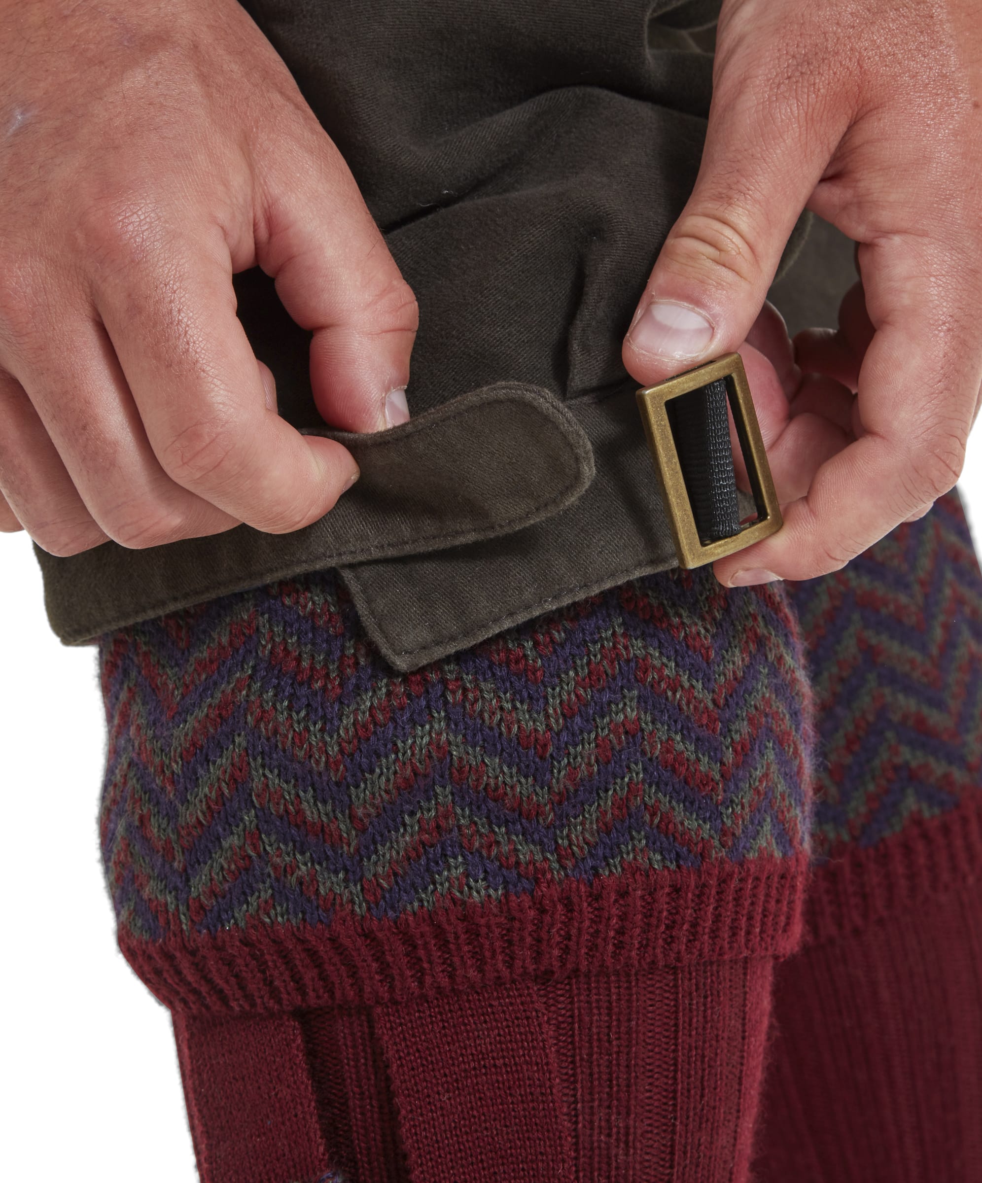 A close-up of the adjustable hem design to the Schöffel Moleskin Trousers for Men in Green. An antiqued brass buckle can be used to adjust the width to fit the wearers calves. This helps ensure a nice fit but also retains a level of body temperature during cold winter shoot days. A chevron design burgundy shooting sock can be seen.