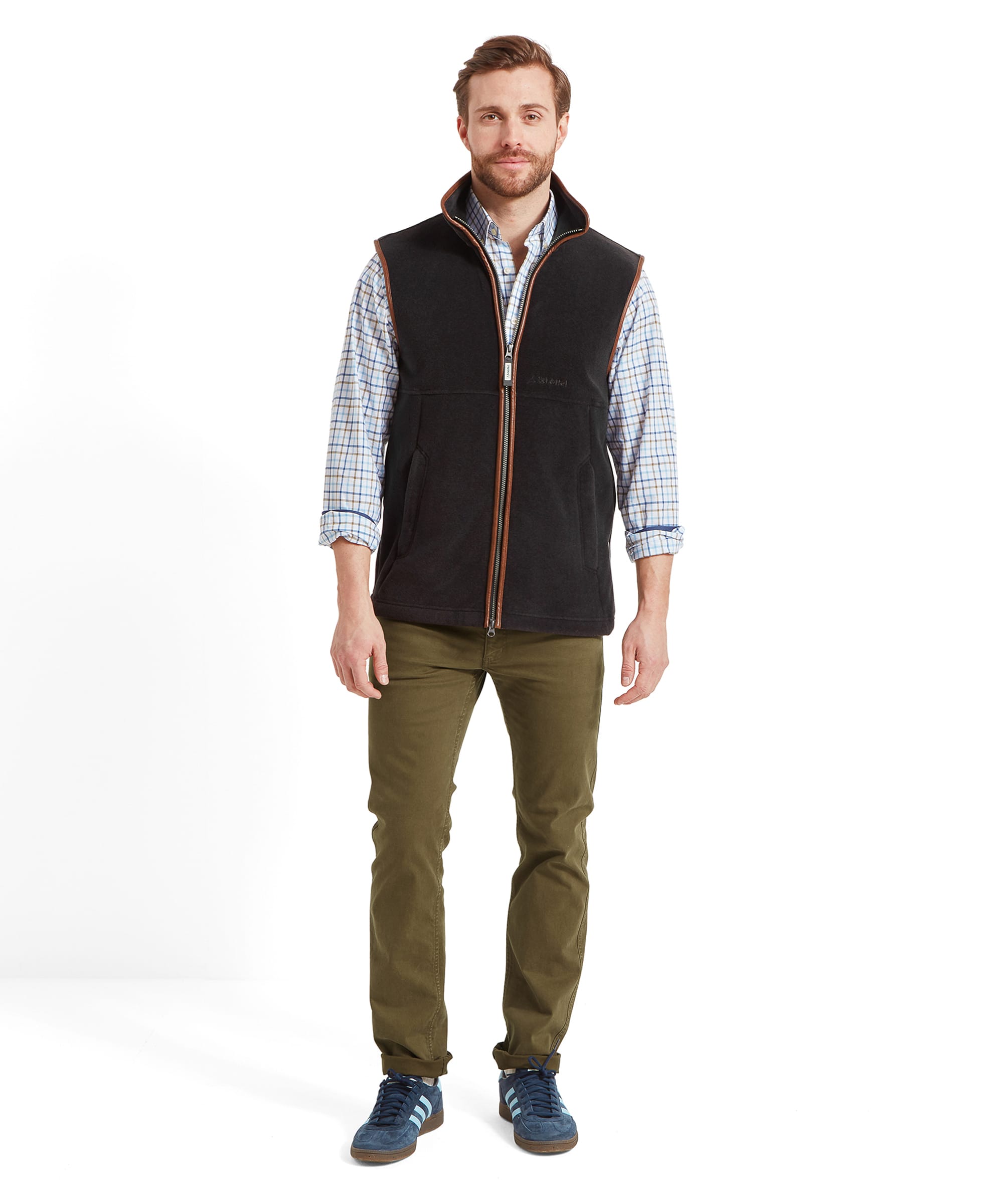 Full body view of a man standing, showcasing the Schöffel Oakham Fleece Gilet for Men in Grey paired with green trousers and blue sneakers.