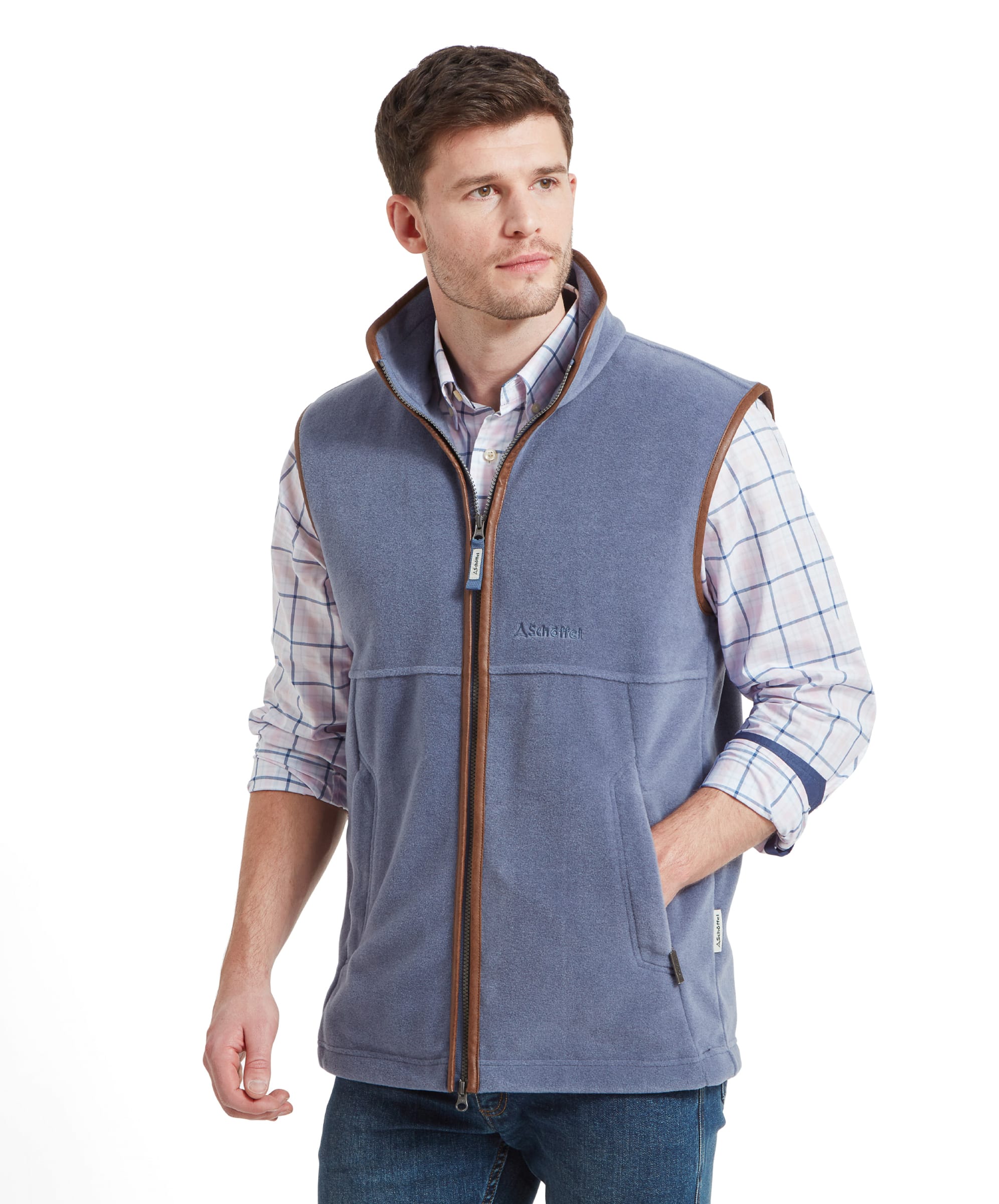 A man wears the Schöffel Oakham Fleece Gilet for Men in Light Blue with a checked shirt and denim jeans. He has his right hand in his pocket and looking to his right.