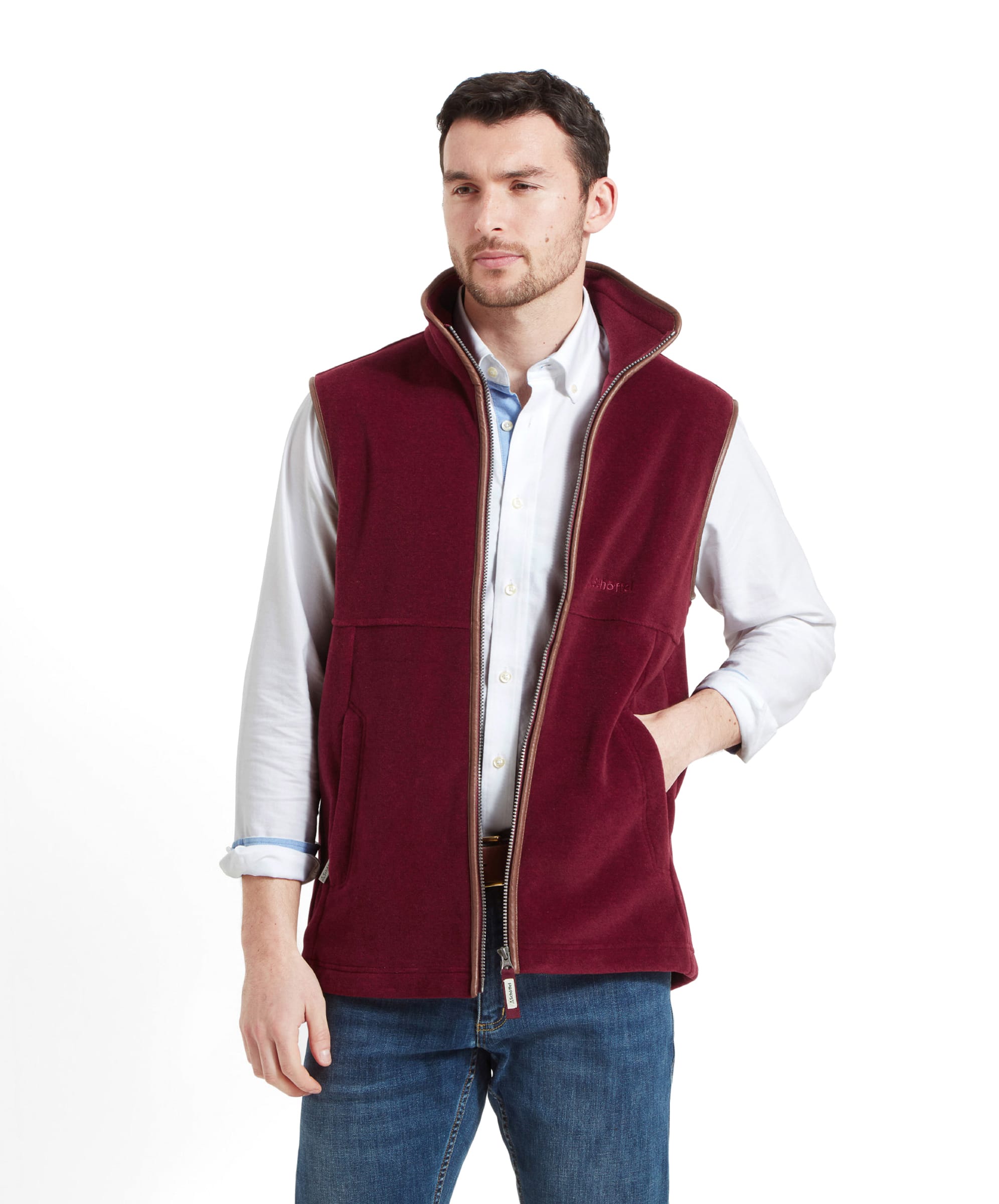 The model poses with a relaxed expression, wearing the Schöffel Oakham Fleece Gilet for Men in Red with his hands in the pockets.