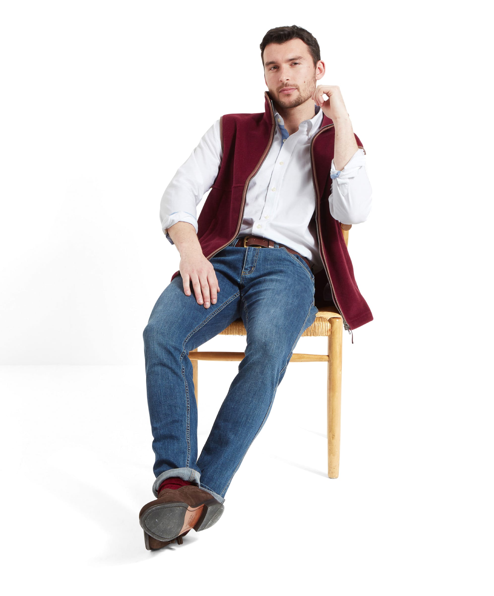 Seated comfortably, the model looks forward while wearing the Schöffel Oakham Fleece Gilet for Men in Red.