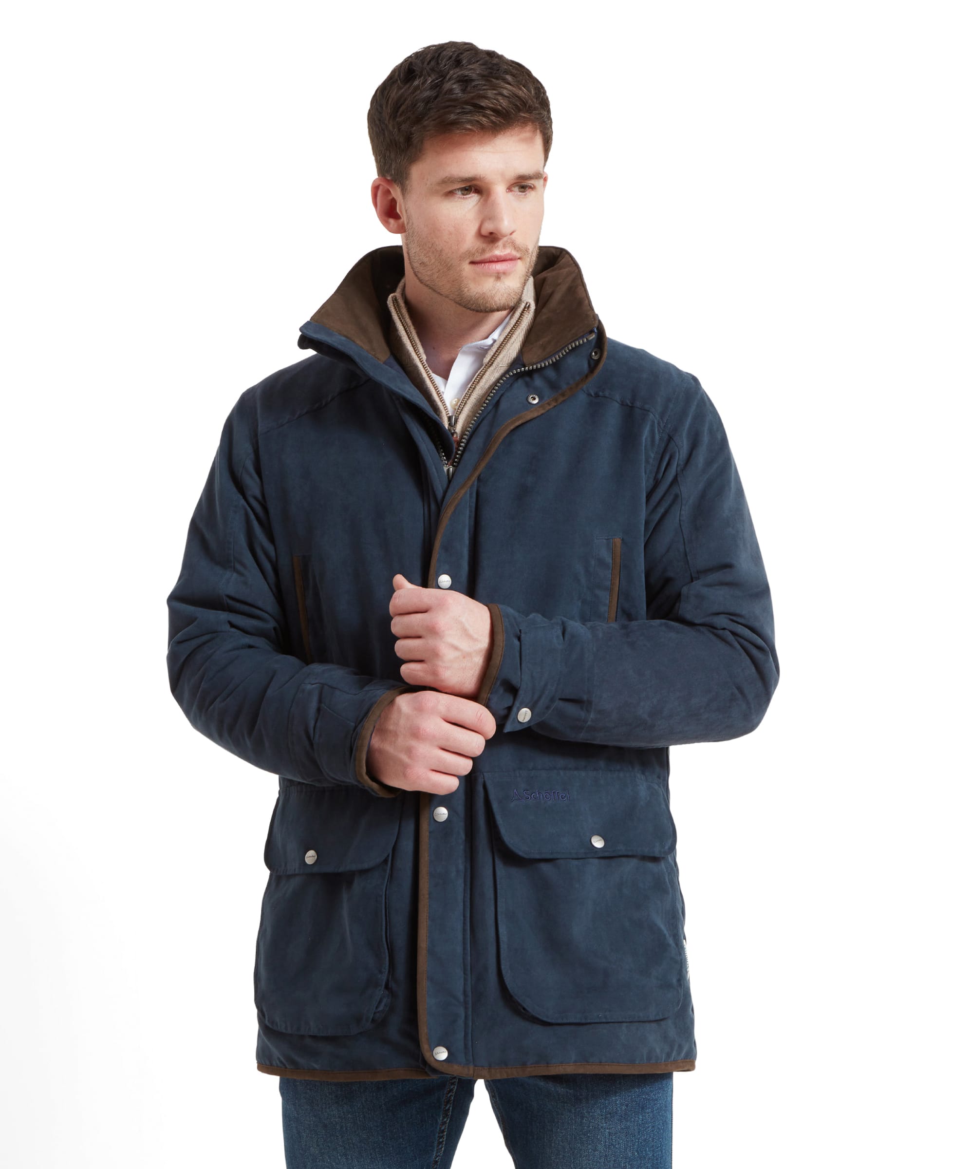 A man models the Schöffel Oundle Country Coat in navy, showing off the front zip and button closure, standing with hands at the collar.