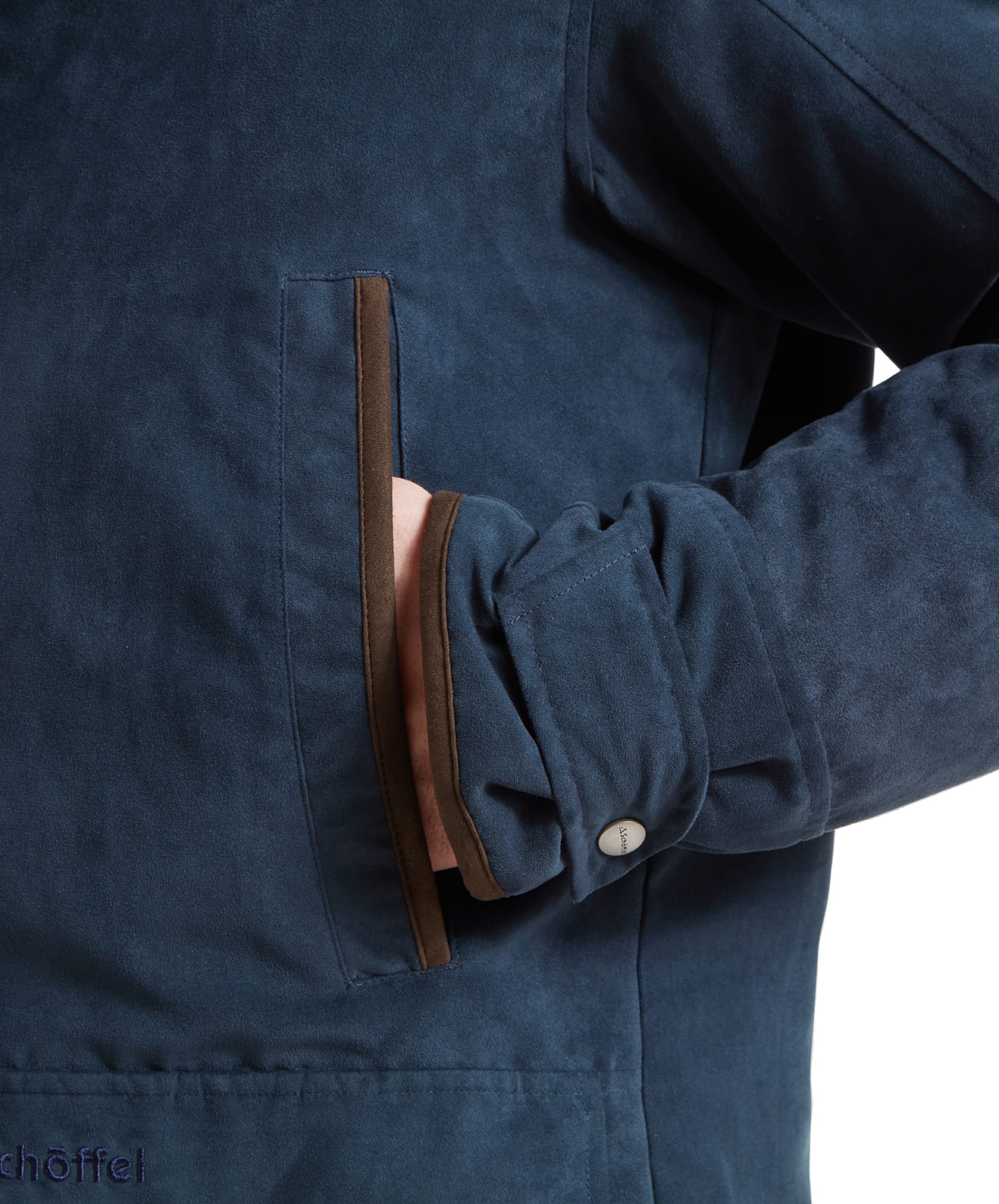 Close-up of the coat's handwarmer pocket, with the model's hand partially inside, showcasing the pocket's trim and button detail.