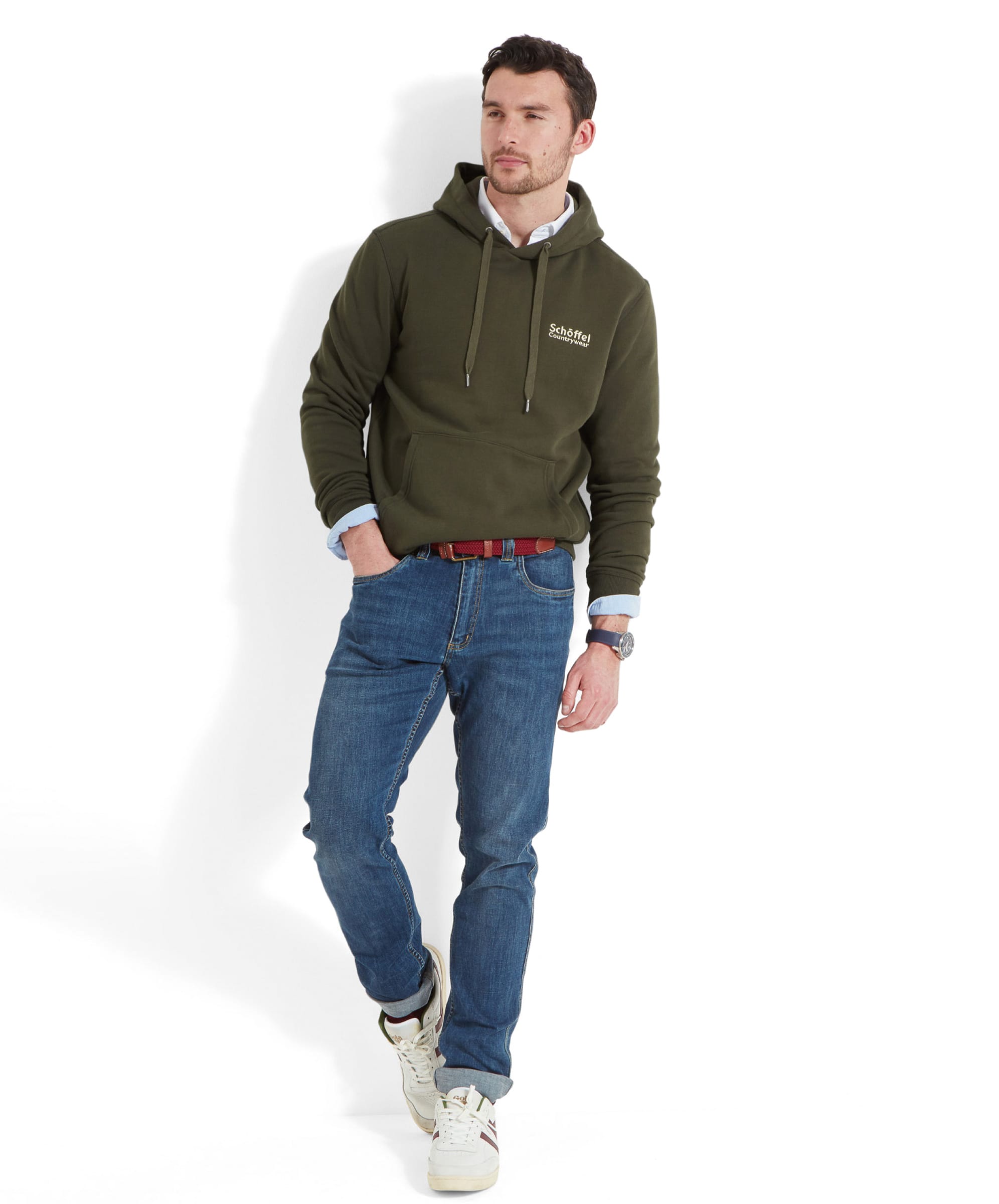 A man walking while wearing Schöffel Pentire Heritage Hoodie for Men in Green, paired with jeans and trainers, highlighting the casual look.