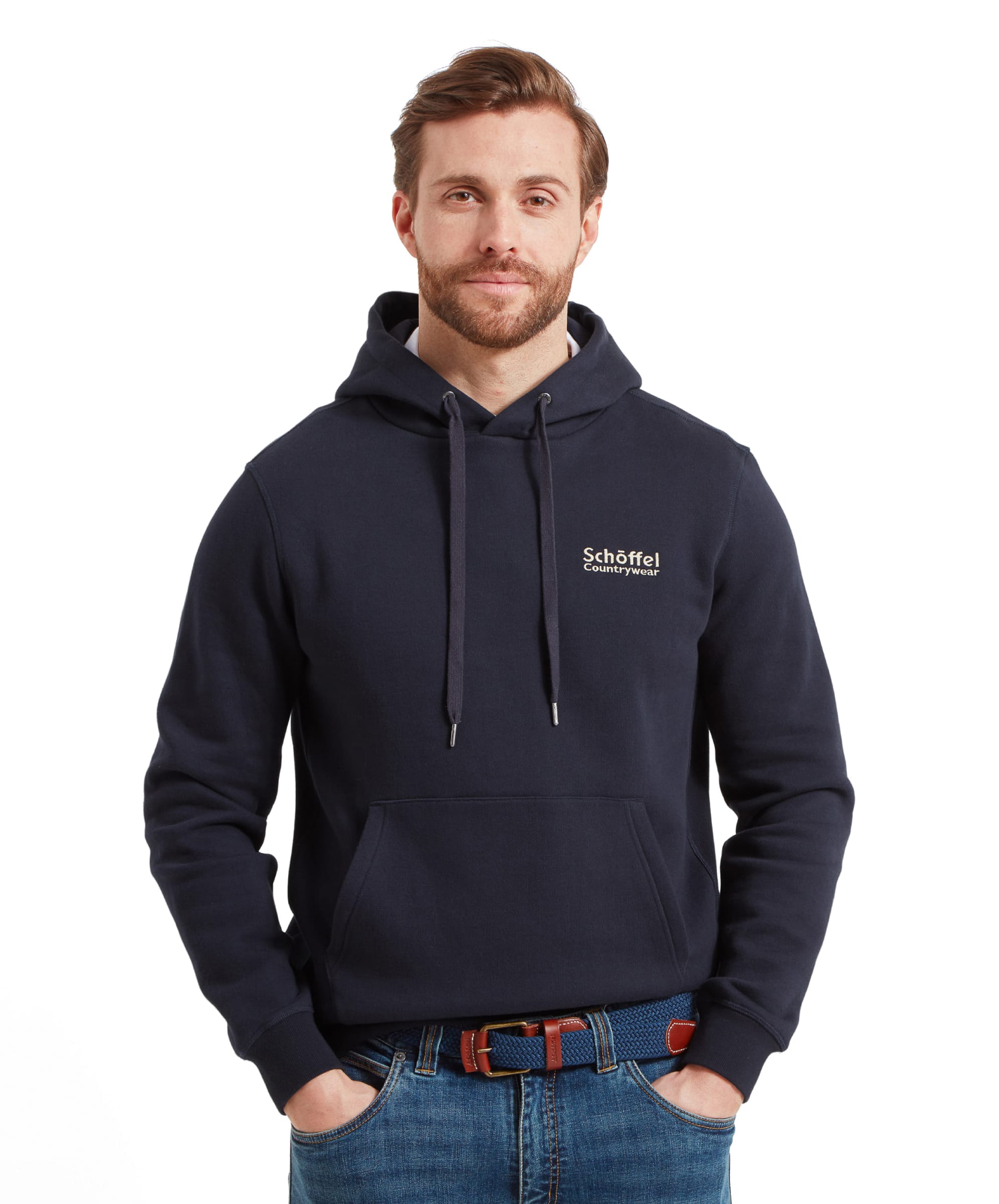 A man is wearing the Schöffel Pentire Heritage Hoodie for Men in Navy, standing with his hands in his pockets. The hoodie features a front pocket and the Schöffel Countrywear logo on the chest.