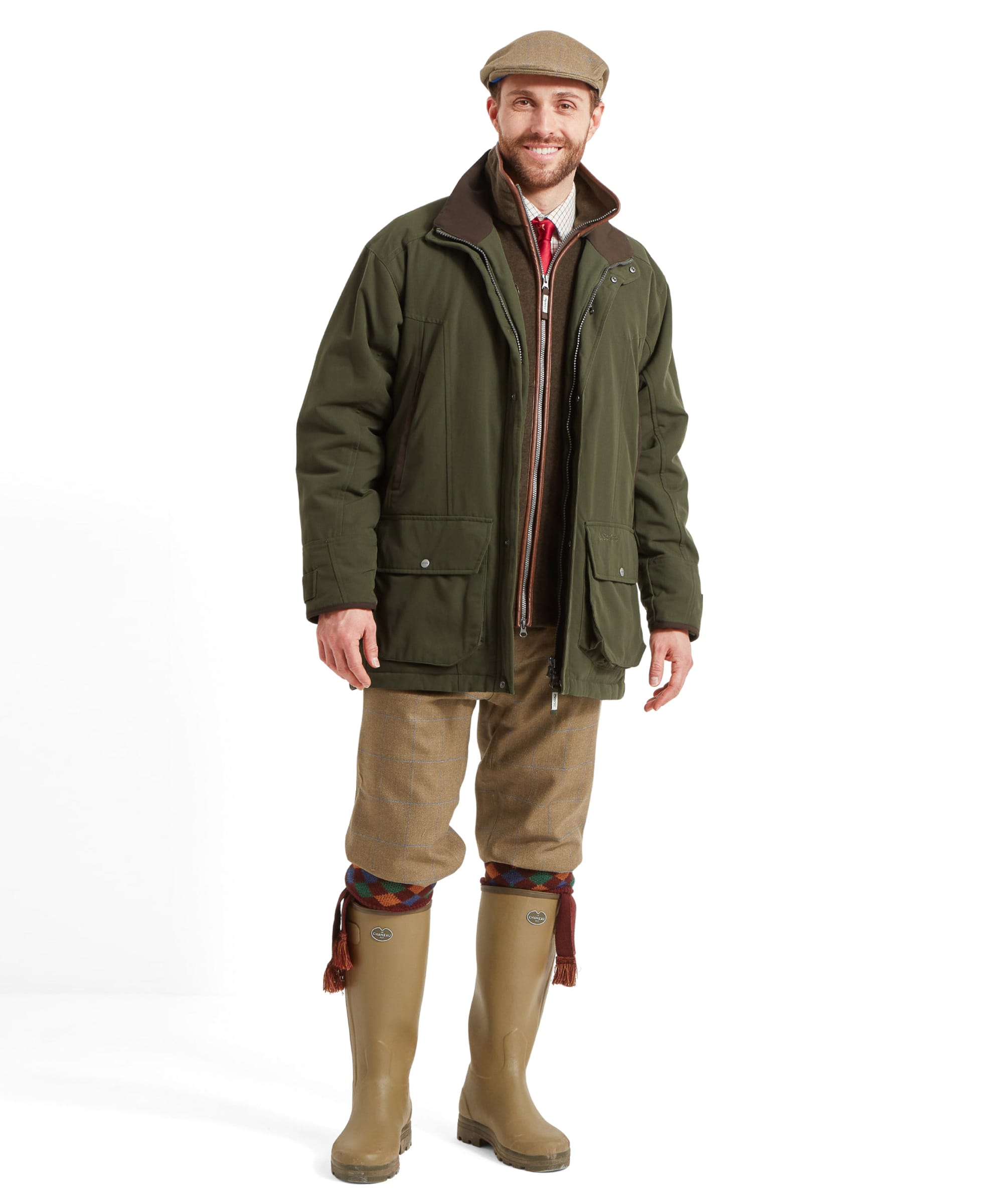 Full-body shot of a man in the Schöffel Ptarmigan Classic Coat for Men in Green, smiling and standing with his hands in the coat's pockets, highlighting the traditional country style.