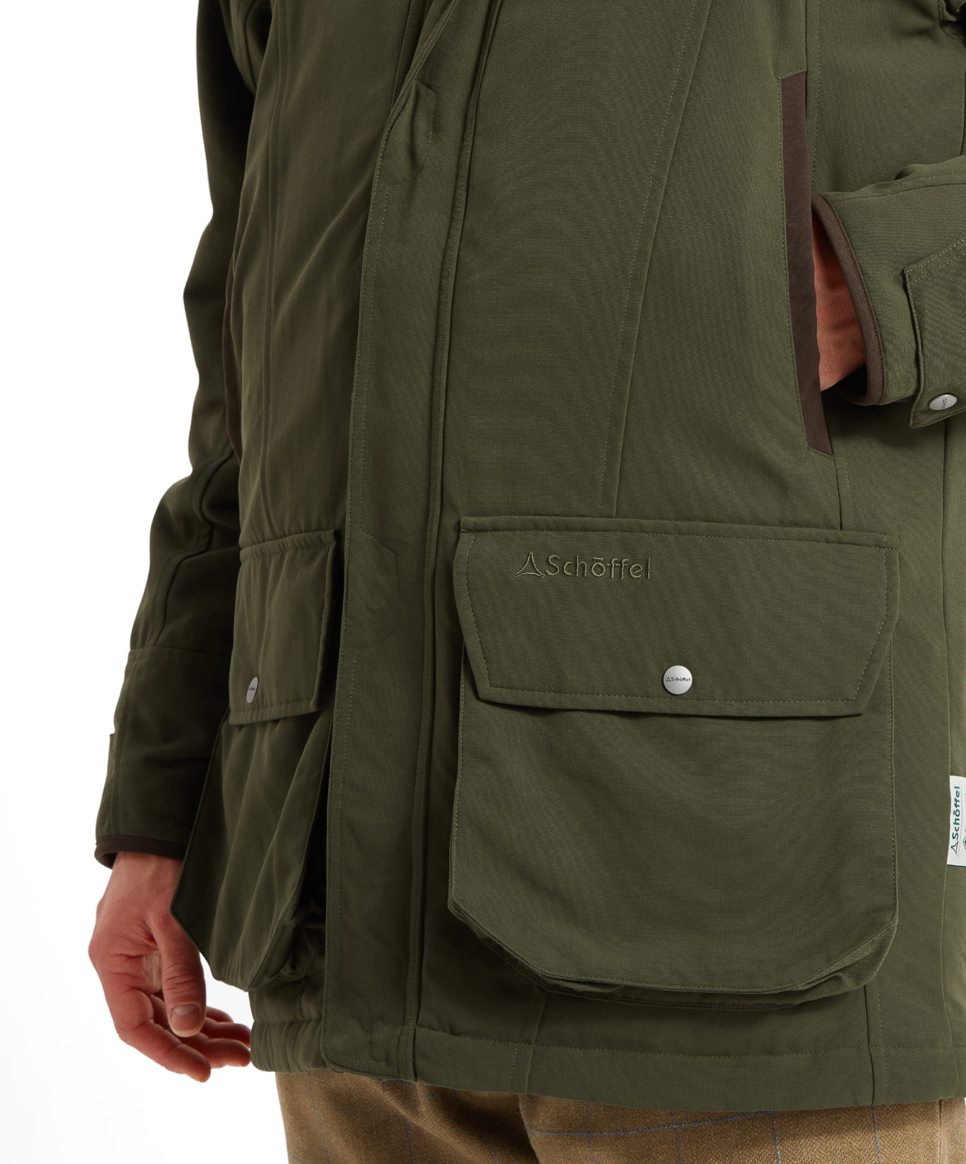 Close-up of the Schöffel Ptarmigan Classic Coat for Men in Green's pocket, with detailed stitching and the Schöffel logo, showing the coat's craftsmanship.